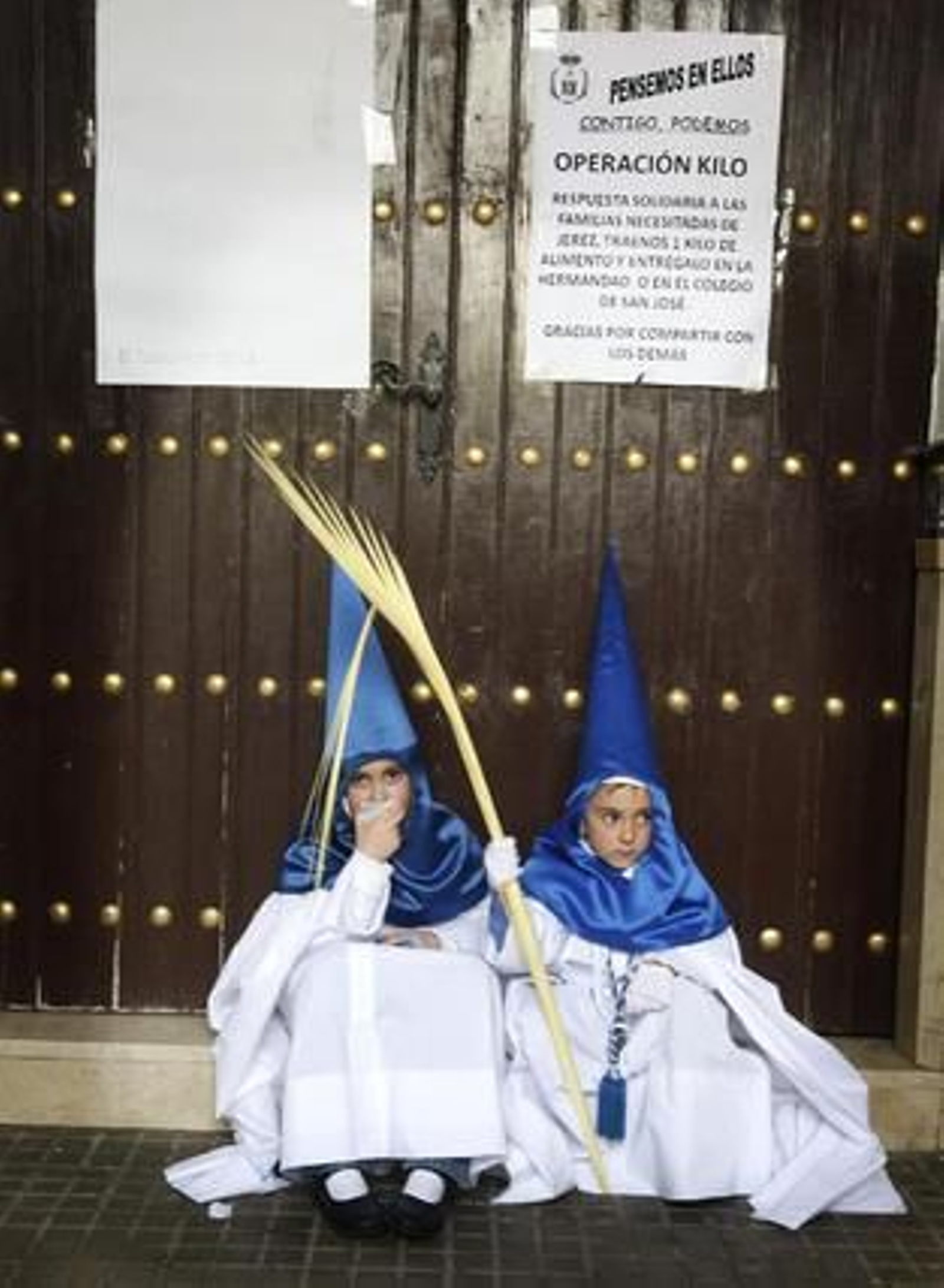 Dos pequeños nazarenos de 'La Borriquita' esperan sentados a que sus mayores ordenasen ponerse en marcha, algo que tardó 45 minutos en suceder.

Foto: Pascual