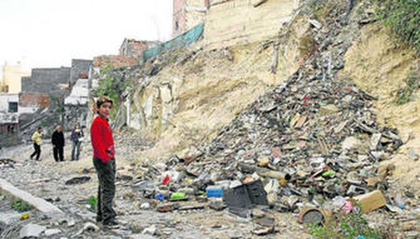 En la imagen, un joven del barrio de la Chanca junto a basura y viviendas en mal estado.