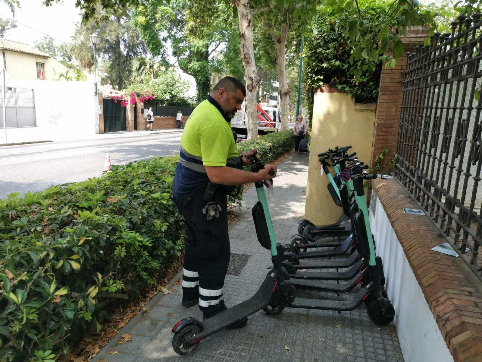 Un operario de la grúa municipal en el momento de retirar varios patinetes mal aparcados.