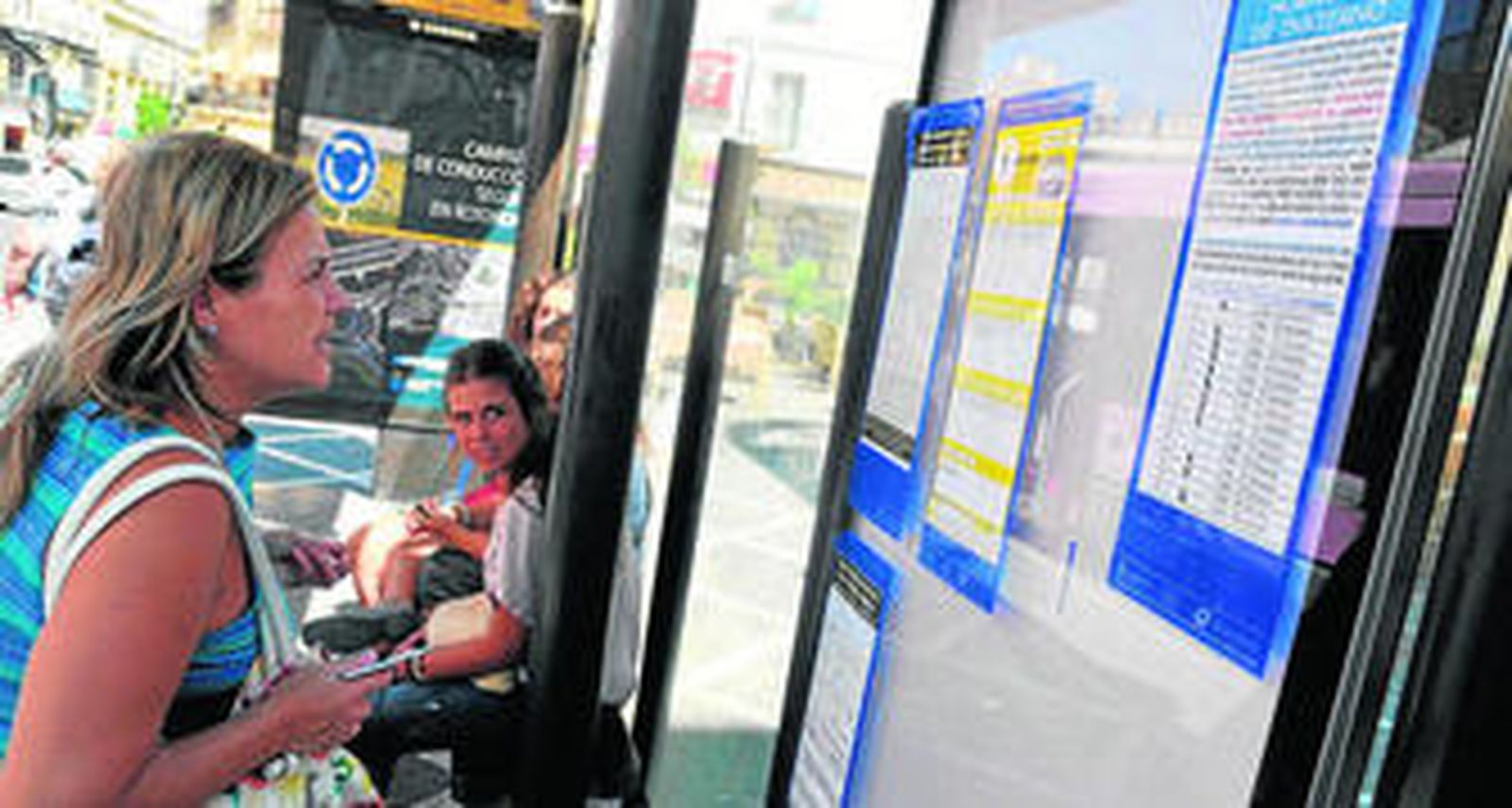 Una mujer observa ayer en una marquesina la nota informativa referente a la no colocación de los horarios de invierno.