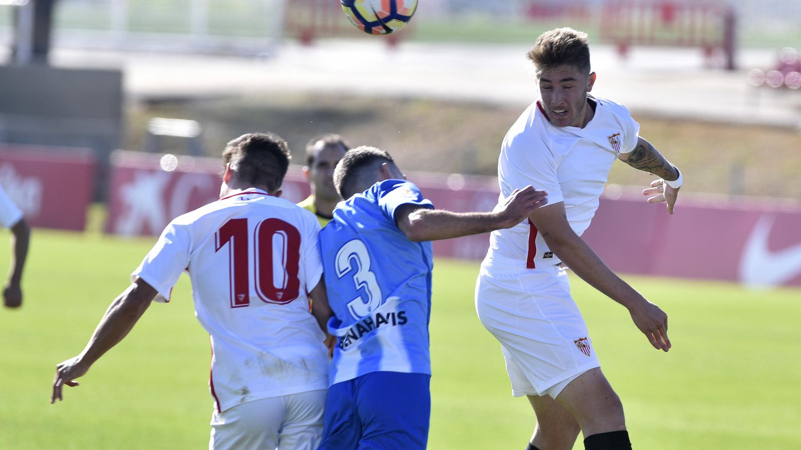 Los sevillistas Casas e Iván, en una disputa aéreo con el malaguista Urbina.