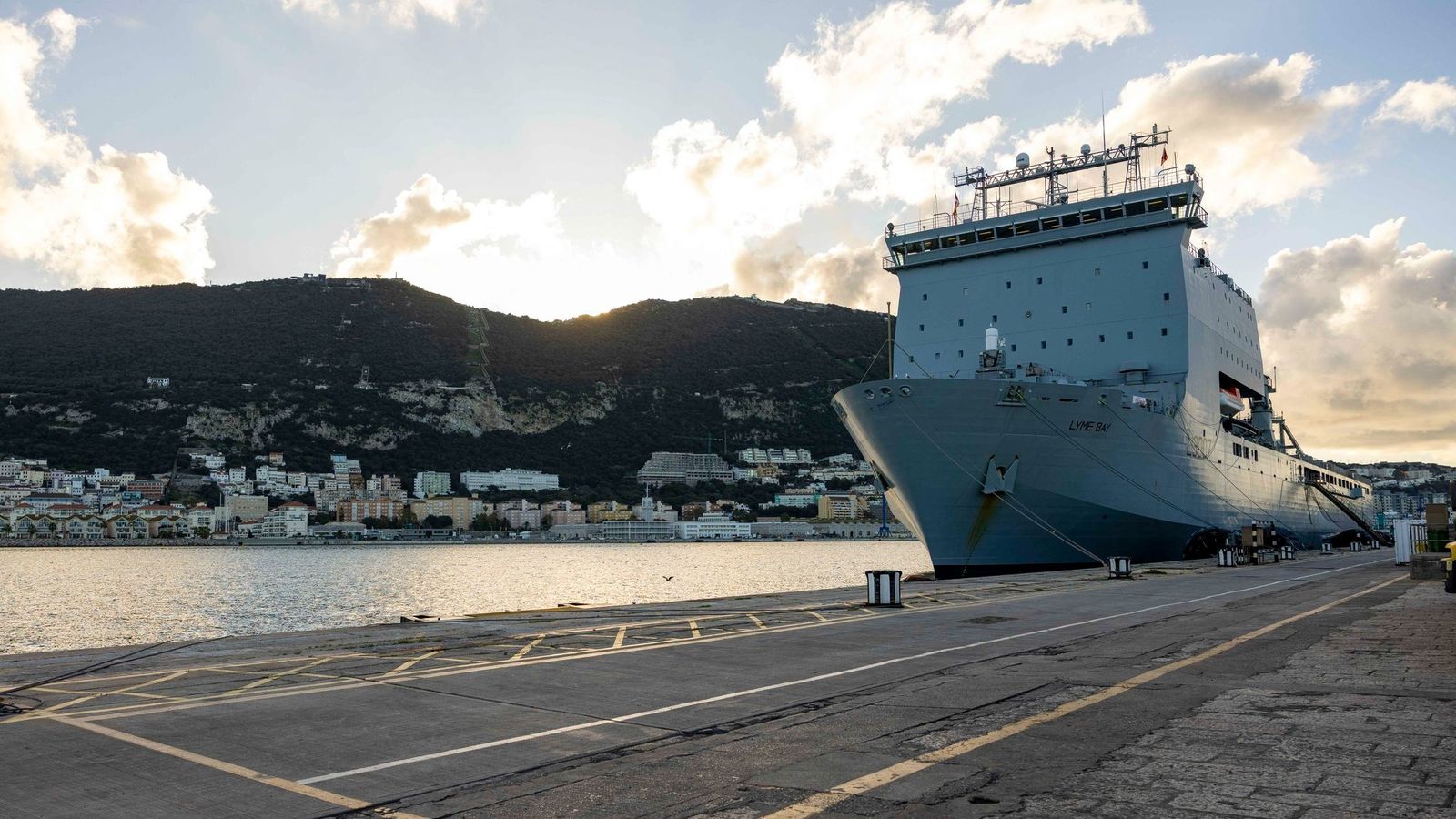 Marineros y operarios coordinan la carga de material logístico con ayuda de una grúa sobre la cubierta del Lyme Bay, junto al South Mole de la base naval de Gibraltar.