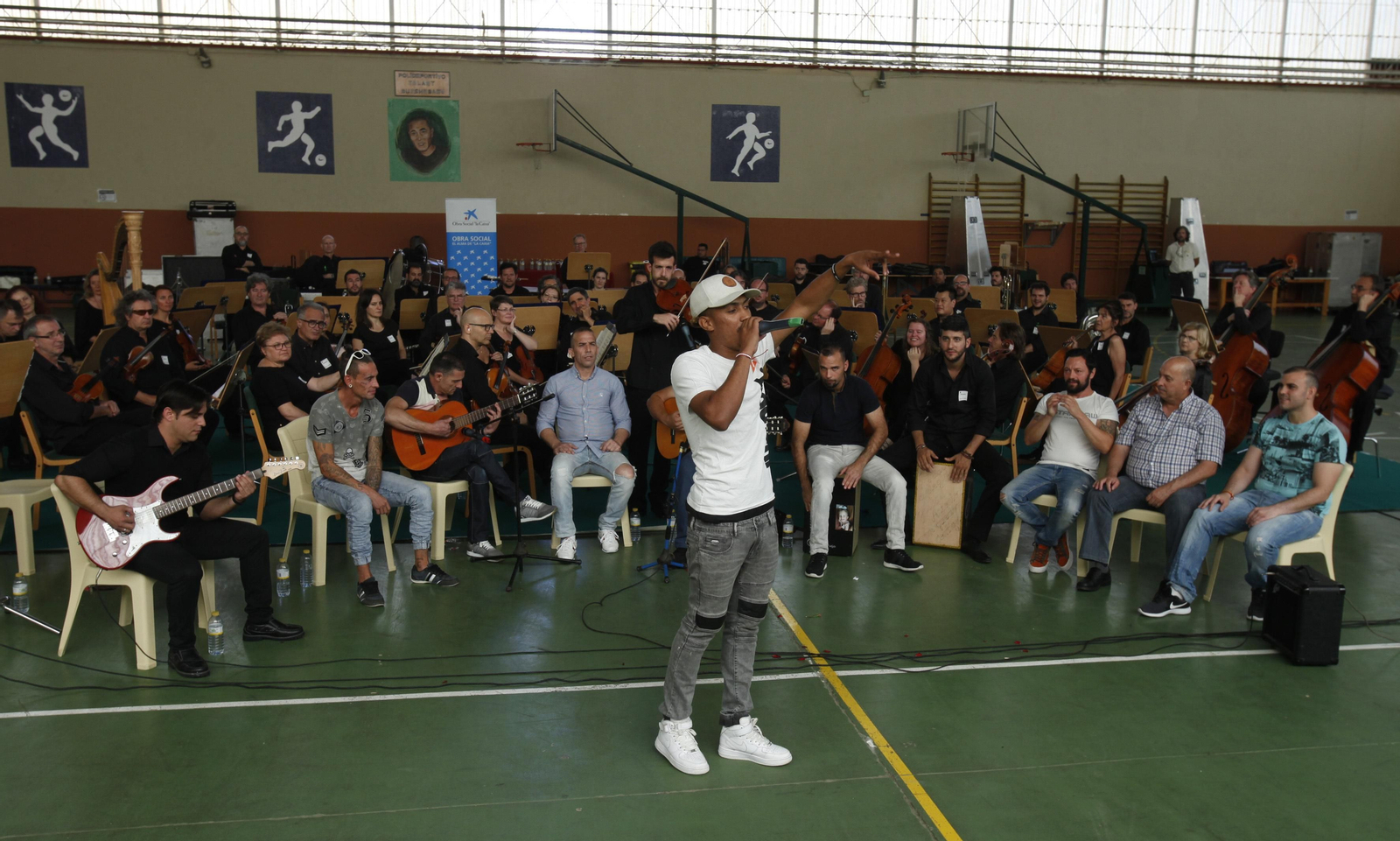 Un recluso de Sevilla 1 canta un rap en Sevilla 1. Detrás, otros reclusos y los músicos de la Sinfónica.
