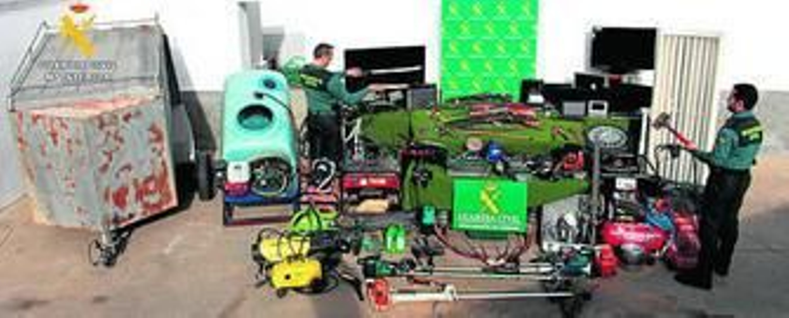 Dos agentes, con los objetos y armas incautadas.