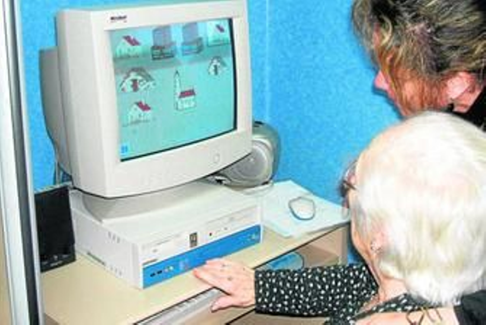 Una auxiliar de AFA Algeciras guía a una señora mientras hace sus ejercicios de estimulación con el ordenador.