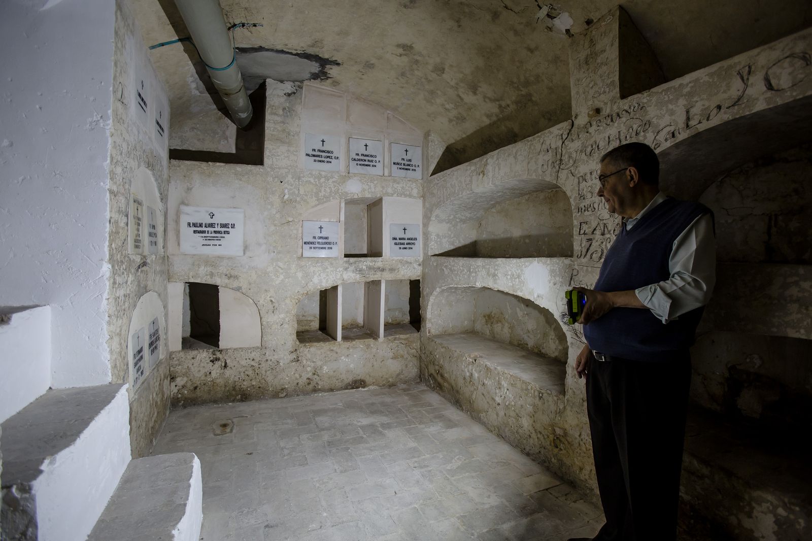 Pascual Saturio dirige el foco que lleva en la mano a las lápidas de los dominicos enterrados en la cripta de la sacristía de Santo Domingo.