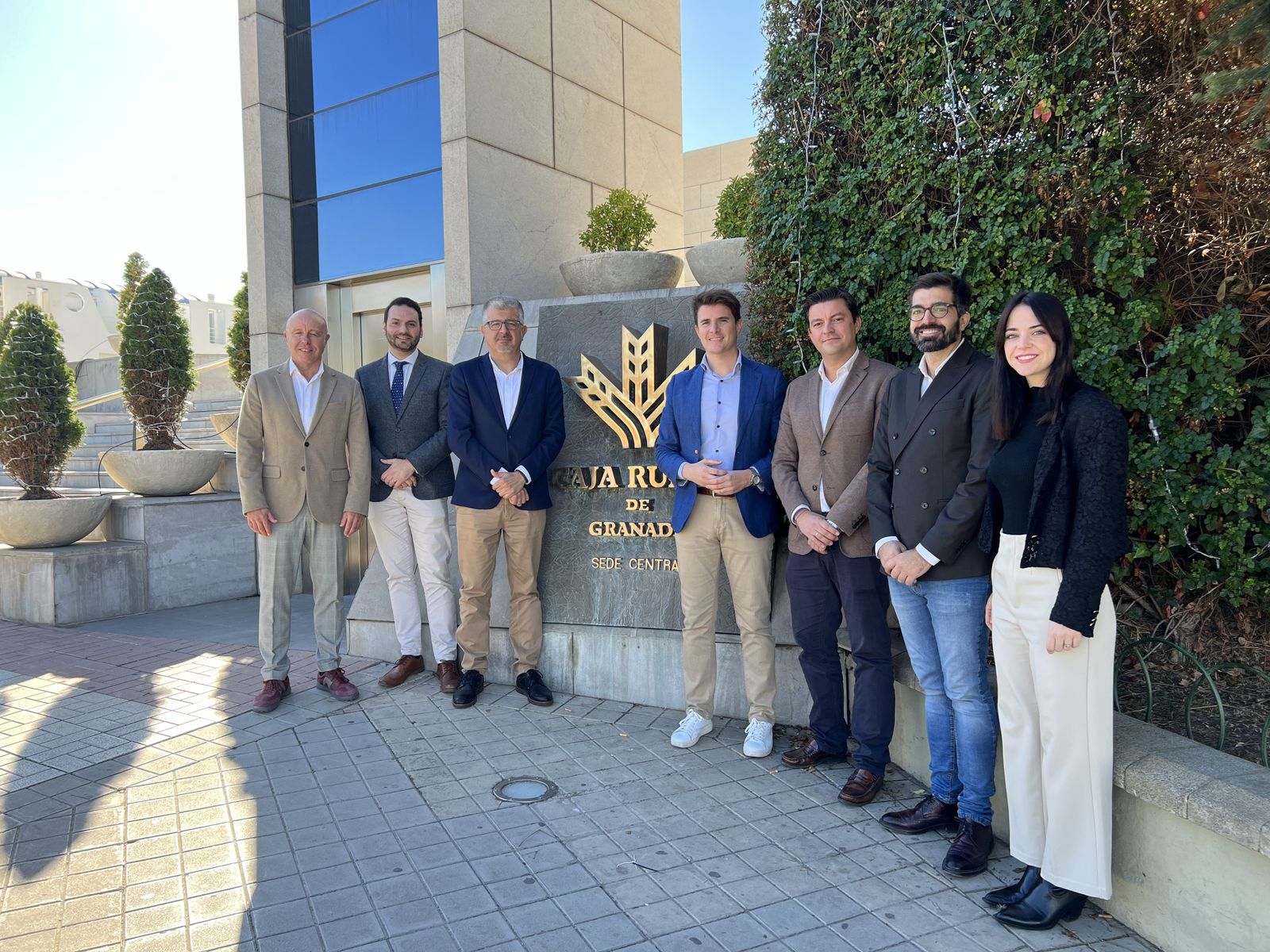 Miembros de Caja Rural y AJE ante la sede de la institución financiera.