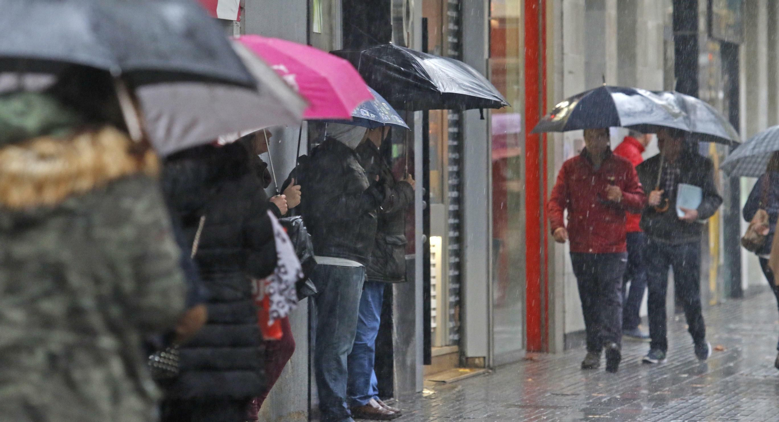 Viandantes con paraguas por Ronda de los Tejares.