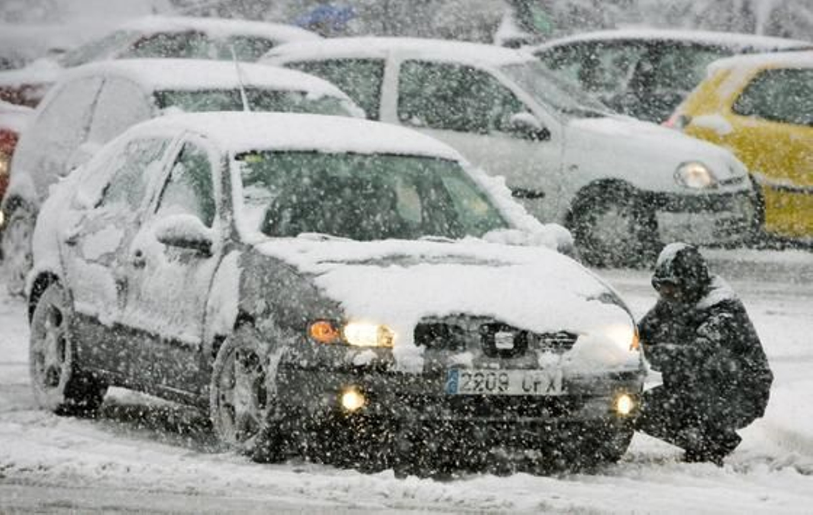 Un conductor coloca la cadenas a las ruedas de su vehículo. /EFE · AFP Photo · Reuters
