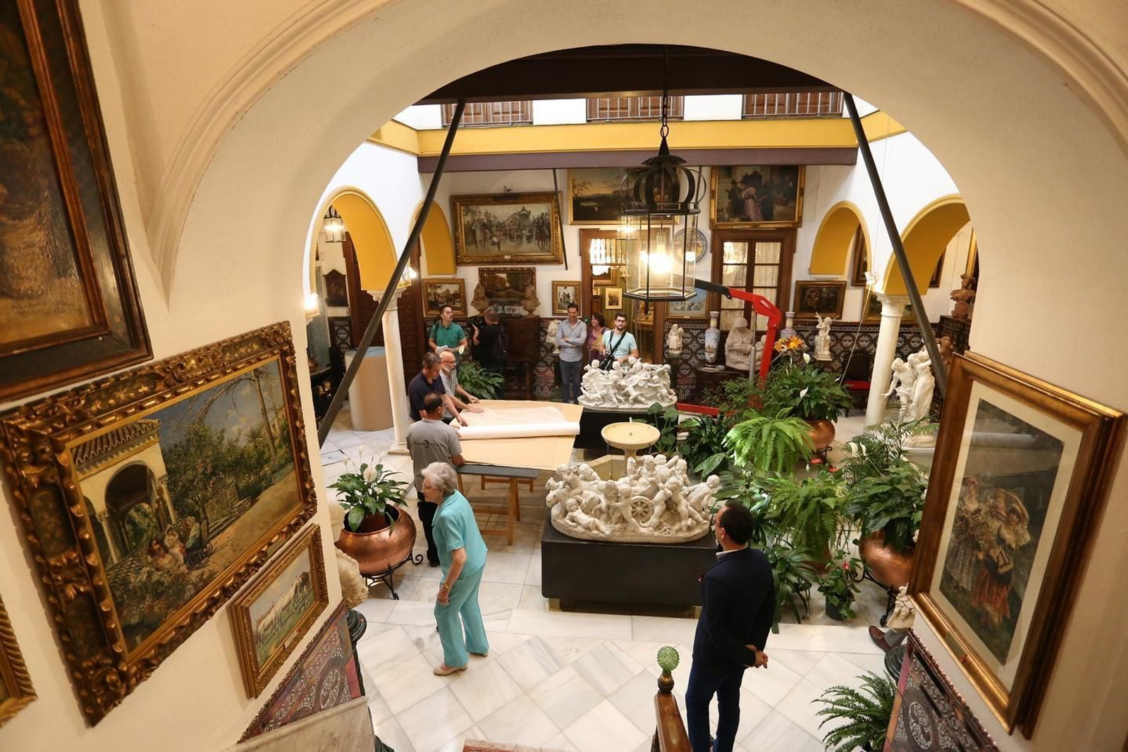 Dolores Mejías, a la izquierda, pasa por el patio repleto de obras listas para el traslado.