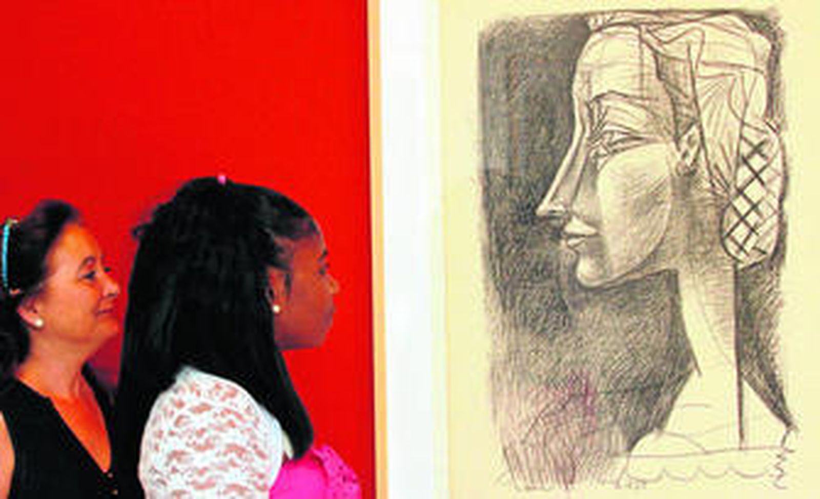 Dos mujeres contemplan uno de los retratos femeninos incluidos en esta exposición.