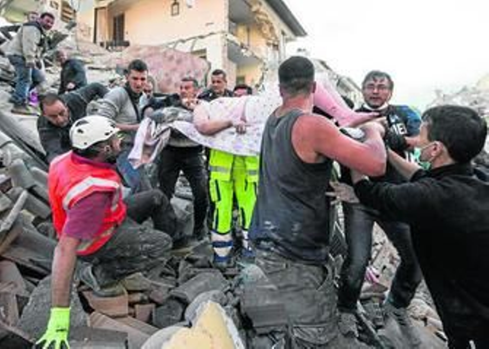Supervivientes y miembros de los equipos de rescate sacan a una mujer de los escombros, ayer en Amatrice.
