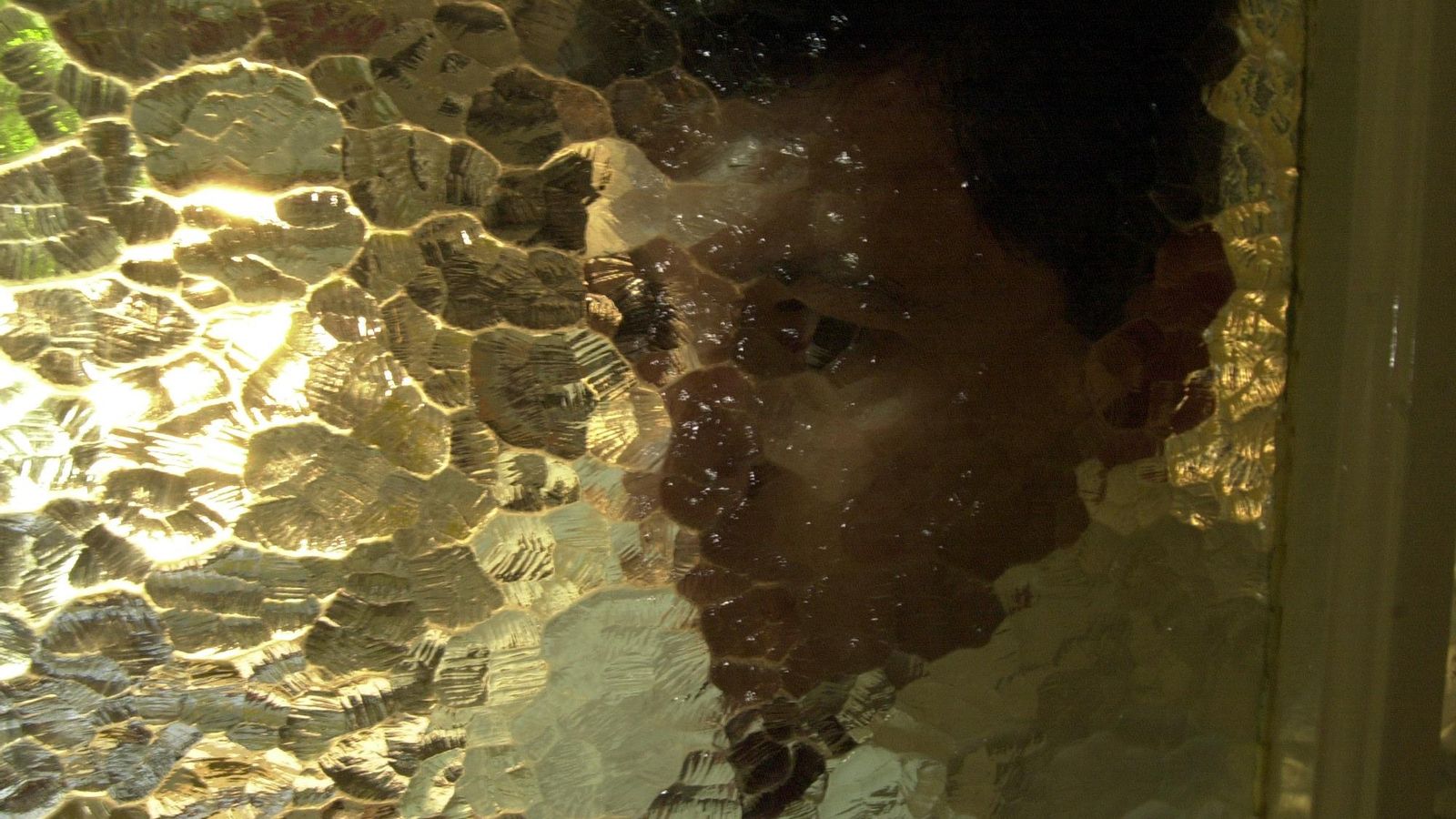 Un detective vigila a una persona tras un cristal.