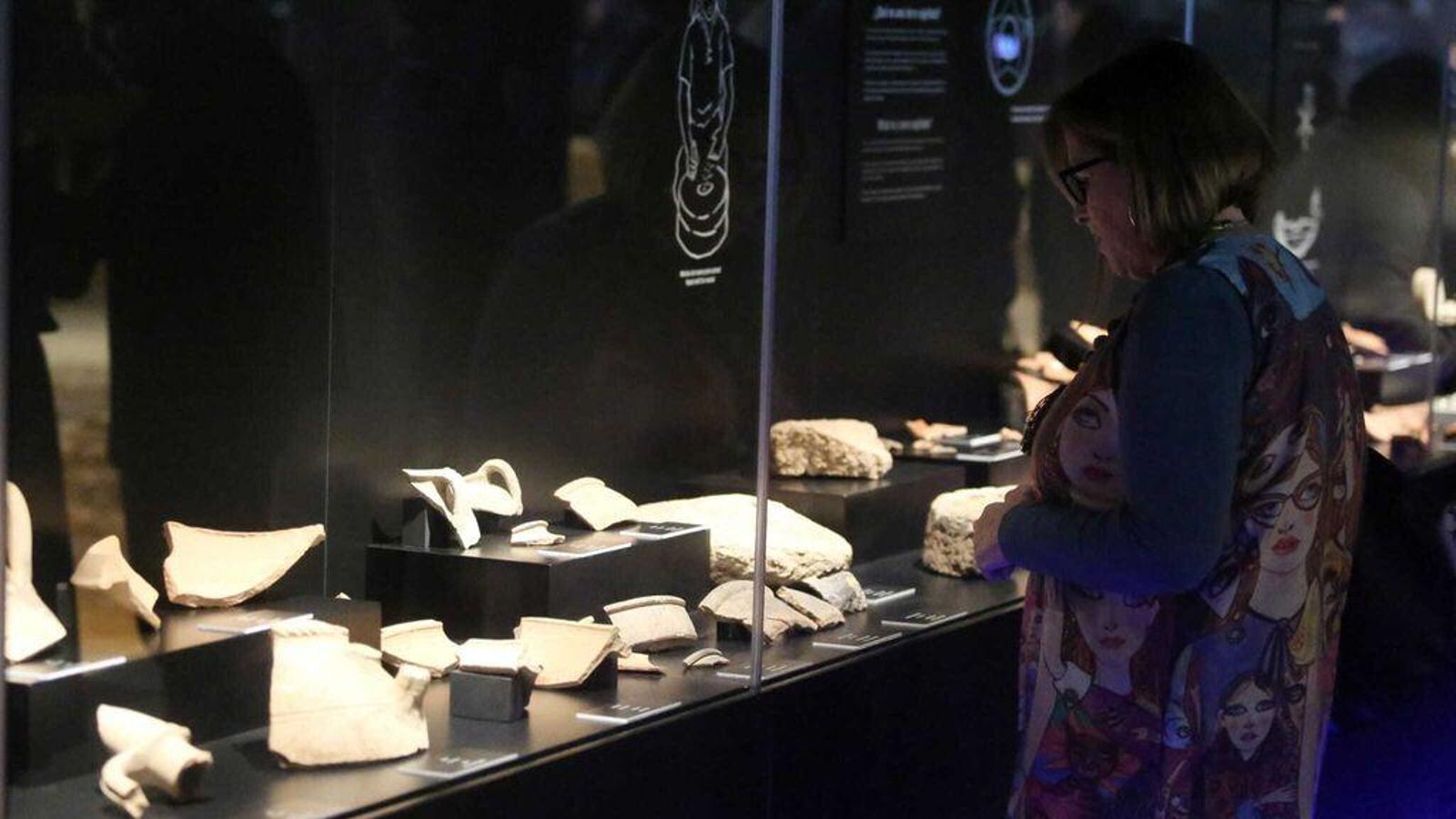 Una visitante observa los restos cerámicos encontrados en el yacimiento.