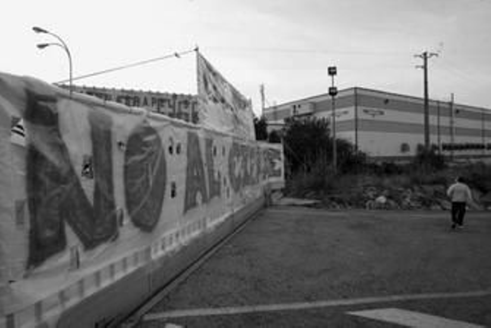 Un ciudadano transita al lado de una de las pancartas que hay colgadas a las puertas de la fábrica Torraspapel.