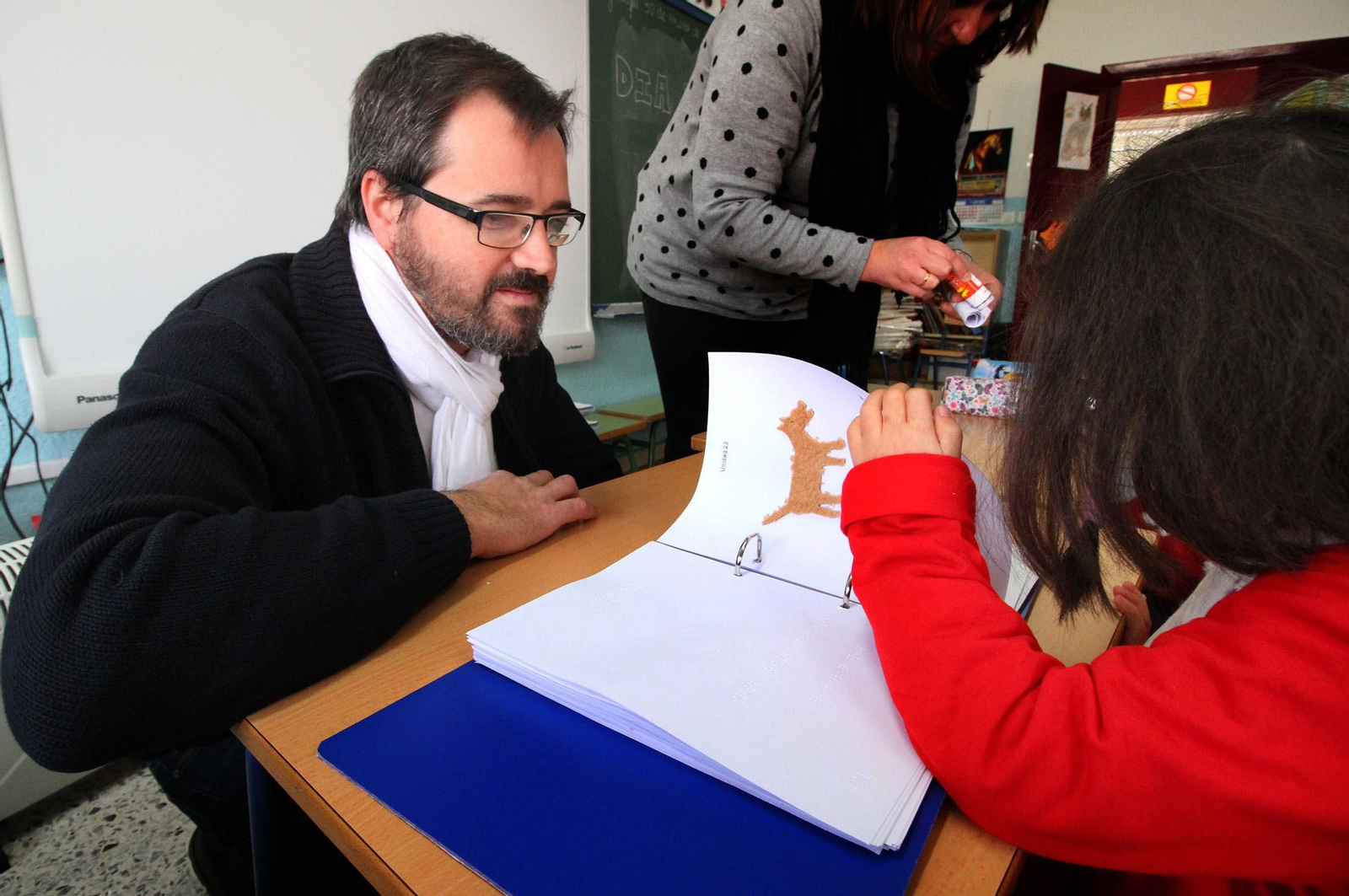 Un profesor de la ONCE ayuda a una alumna con discapacidad visual.