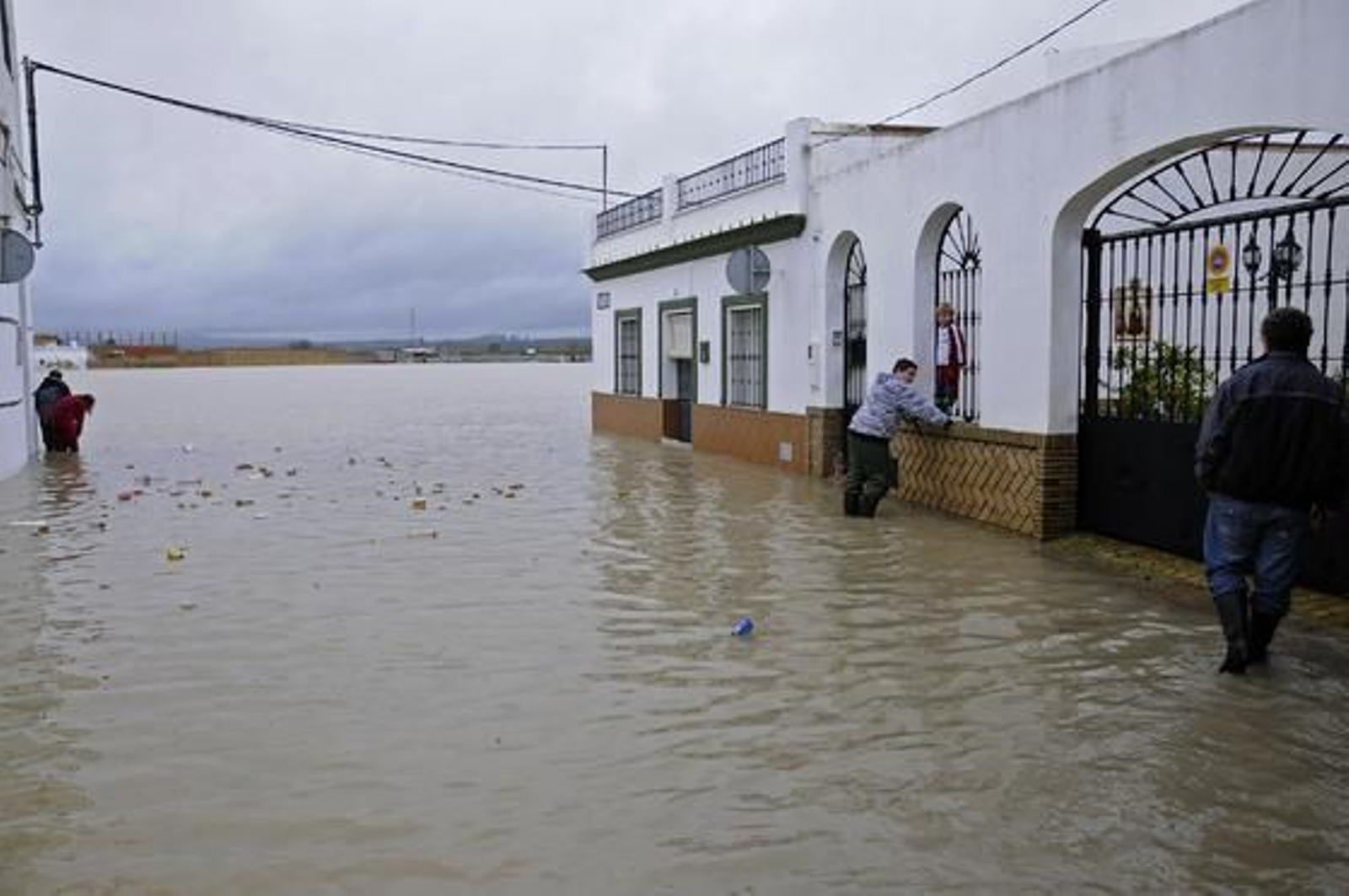 Varios vecinos de Tocina rodeados por objetos que flotan en el agua.  Foto: Juan Carlos Vázquez