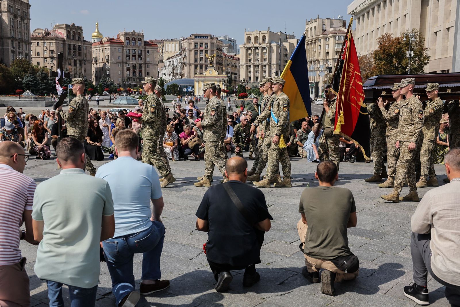 Varias personas se arrodillan al paso del féretro de un militar en Kiev.