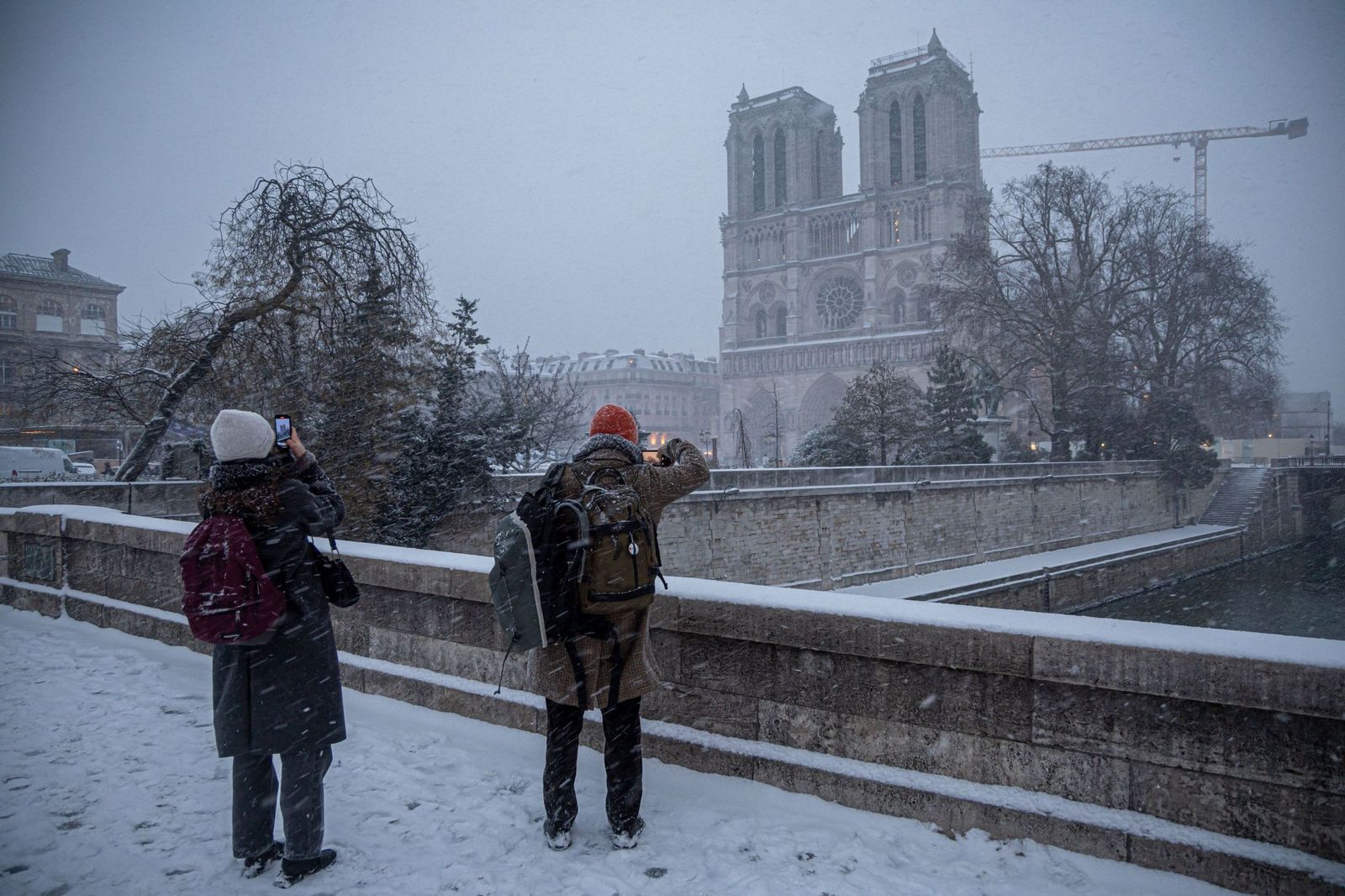 Dos personas observan la catedral de Notre Dame en medio de la nieve.