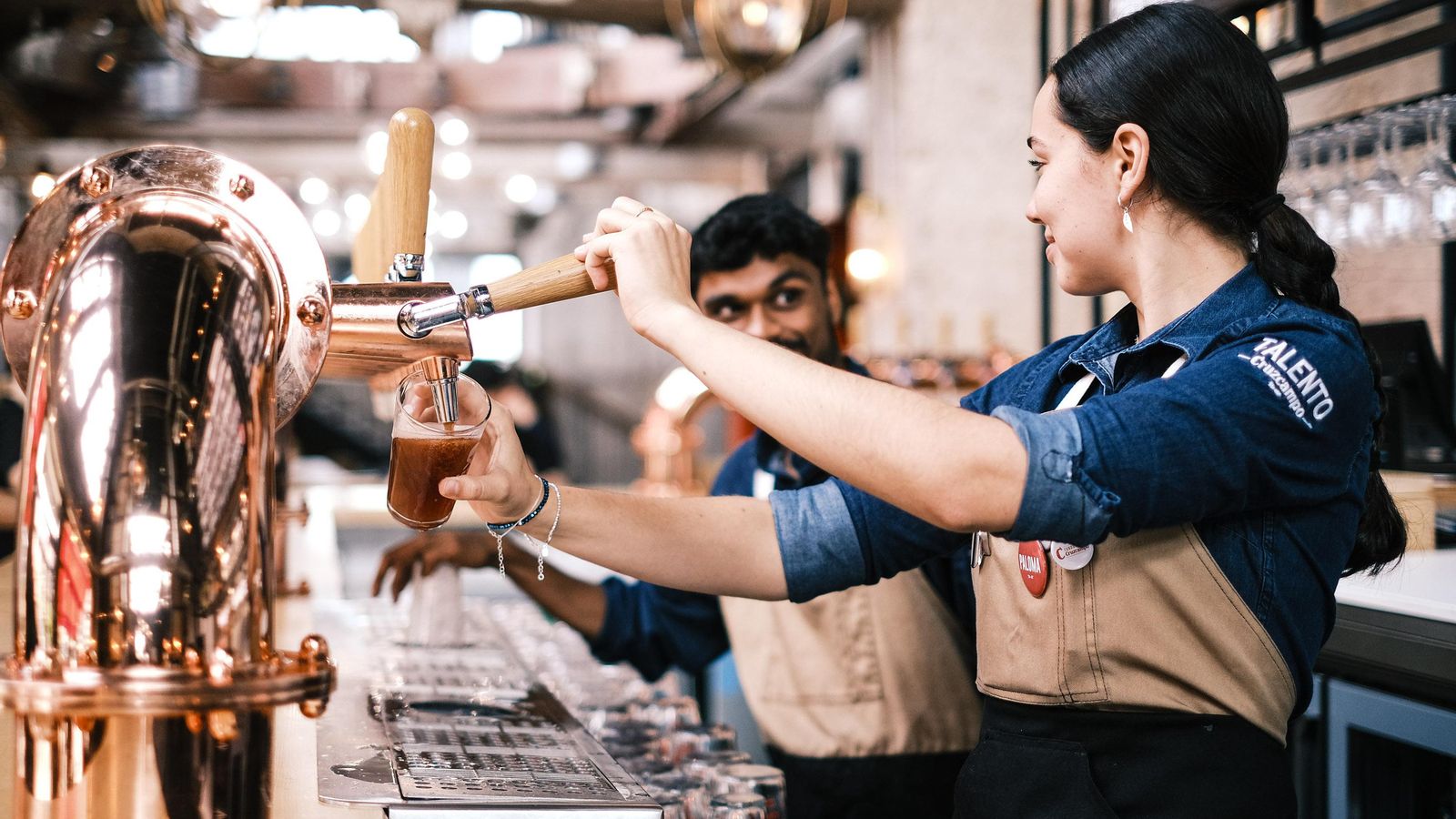 Jóvenes hosteleros sirven cervezas artesanas en Factoría Cruzcampo.