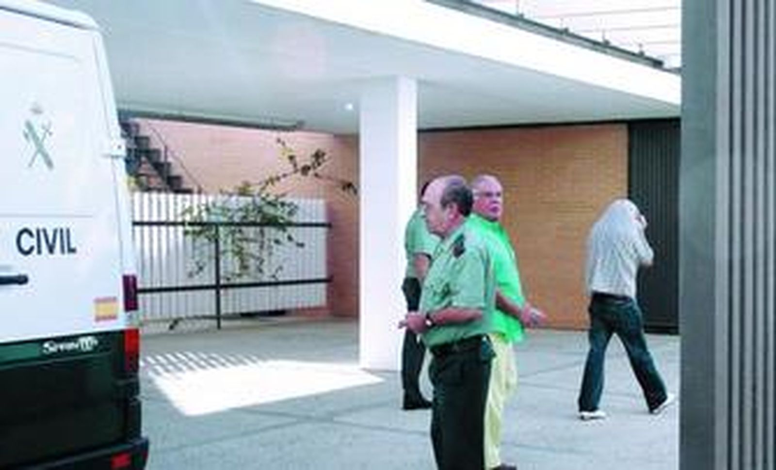 Rodríguez Pueyo -esposado, detrás del agente- mira al fotógrafo a su llegada al Juzgado.