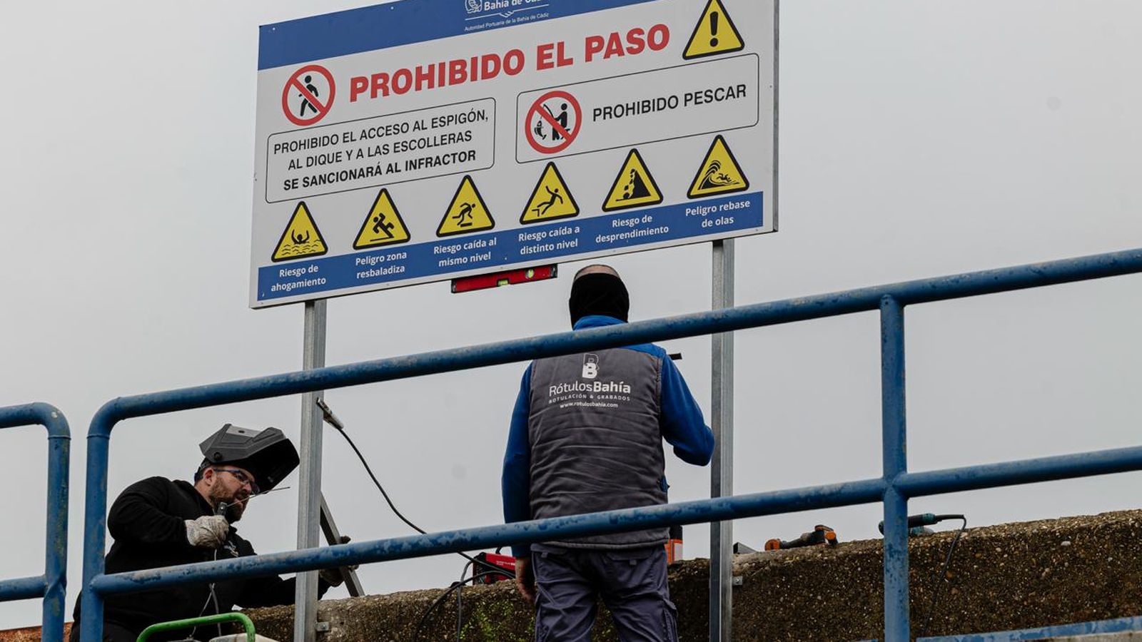 Los operarios que colocaban este lunes el cartel prohibiendo el paso por el paseo dañado en Pascual Pery.