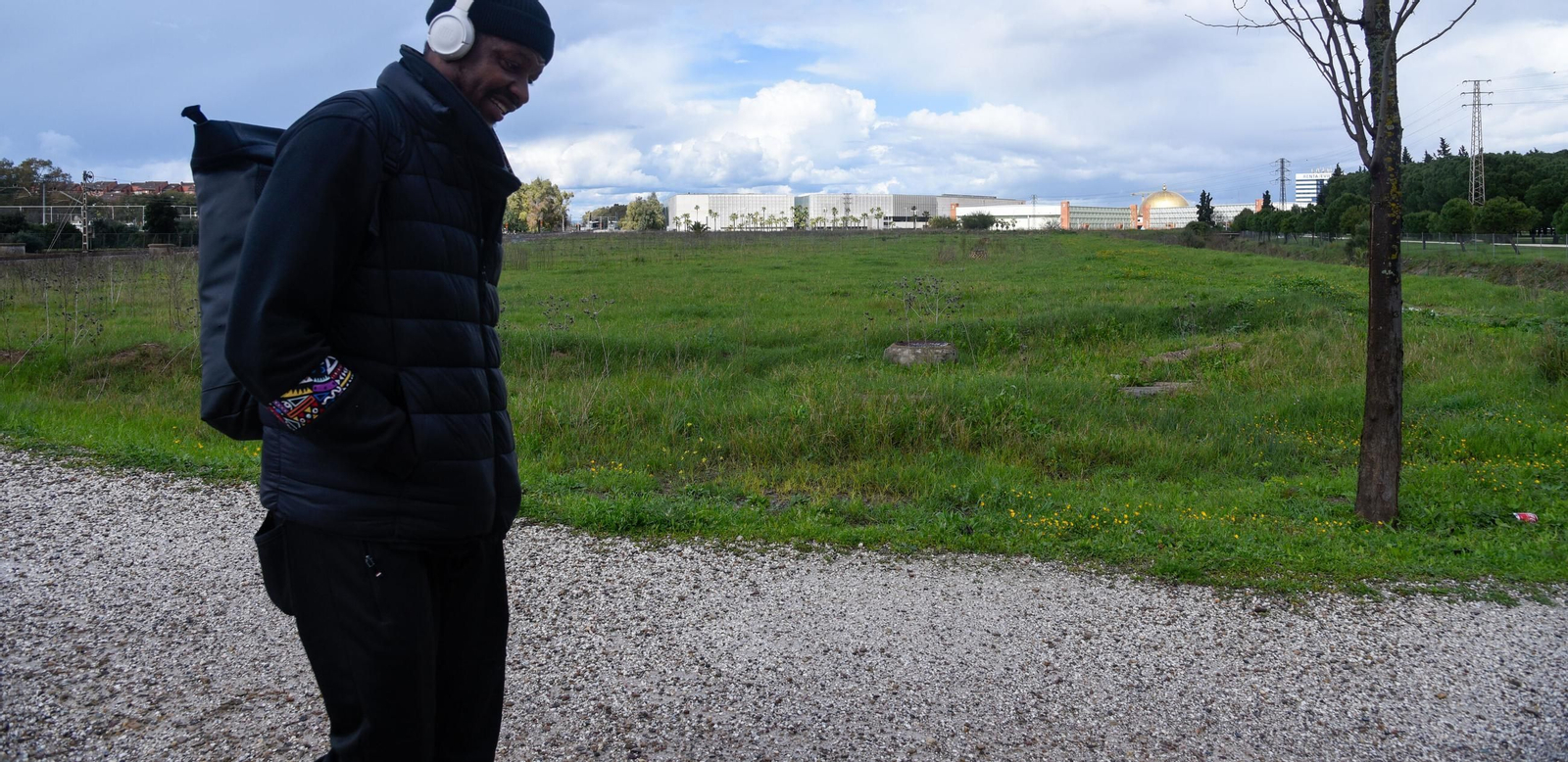 Un hombre pasa a la altura de las parcelas junto a Fibes en las que crecerá el complejo y se construirán VPO.