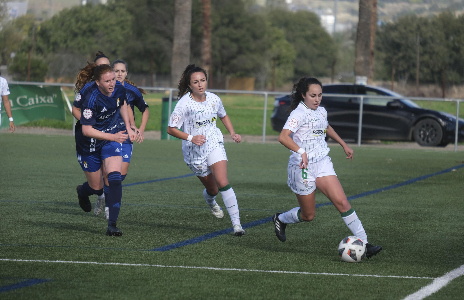 Ana Ocón circula el balón ante la presión de las jugadoras del Oviedo Moderno.