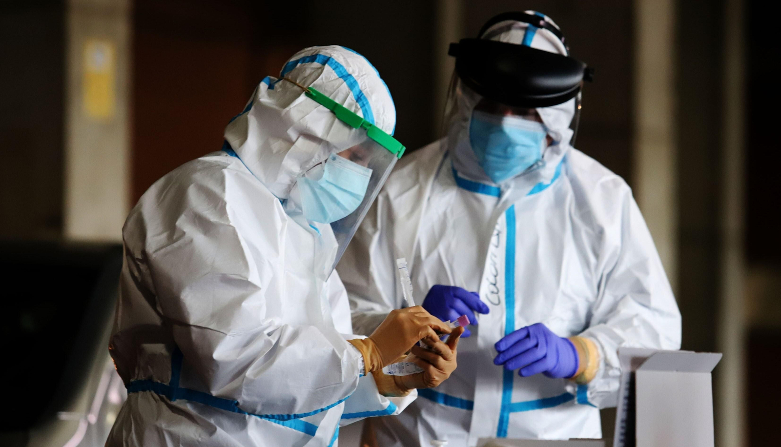 Dos profesionales sanitarios recogen muestras en un auto-covid. Dos profesionales sanitarios recogen muestras en un auto-covid.