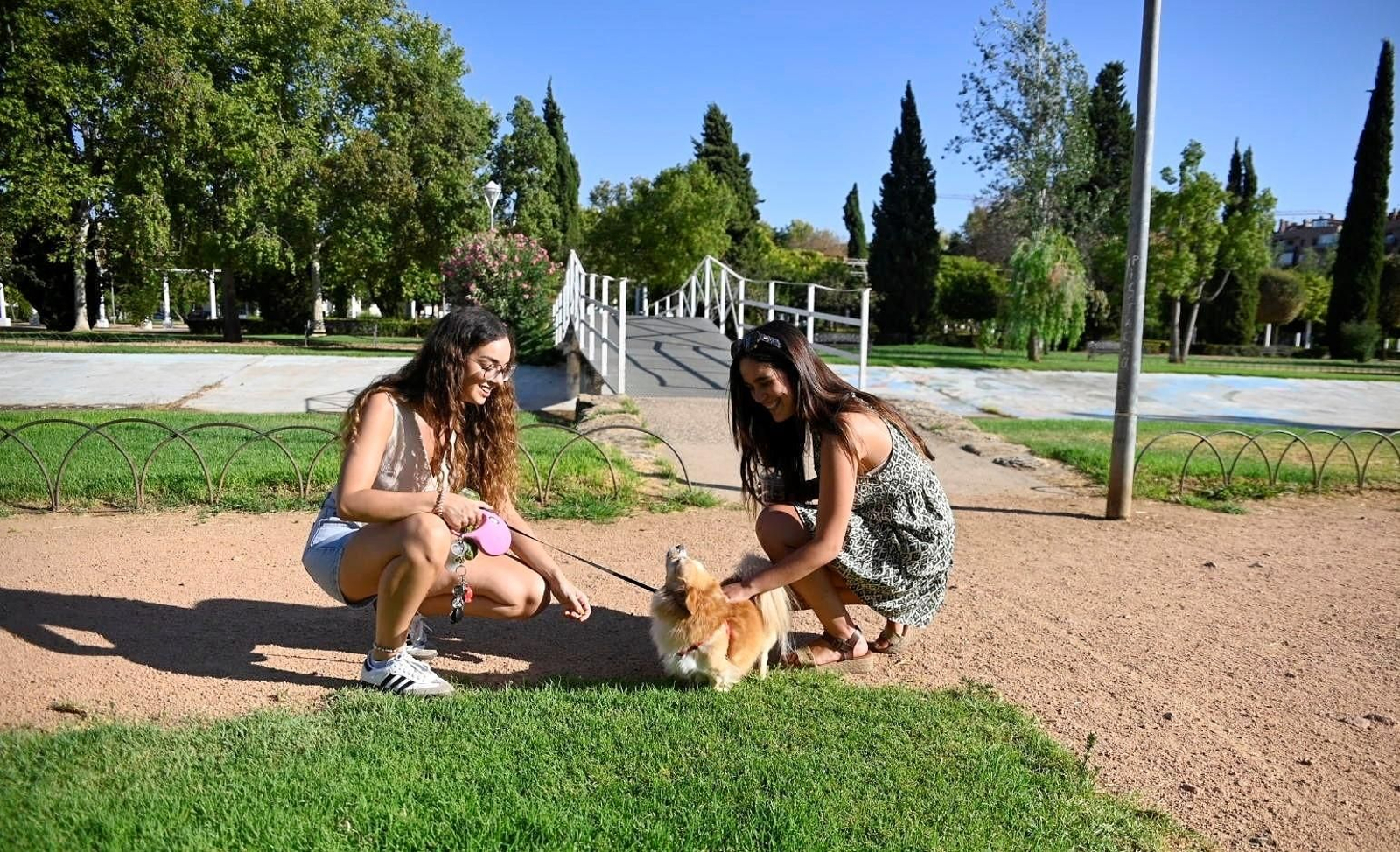 Dos chicas con su mascota en los jardines de Poniente.