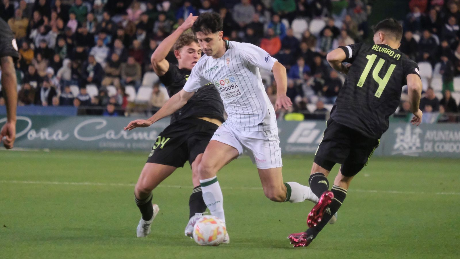 Marco Camus intenta zafarse de la presión de dos jugadores del Real Madrid Castilla.