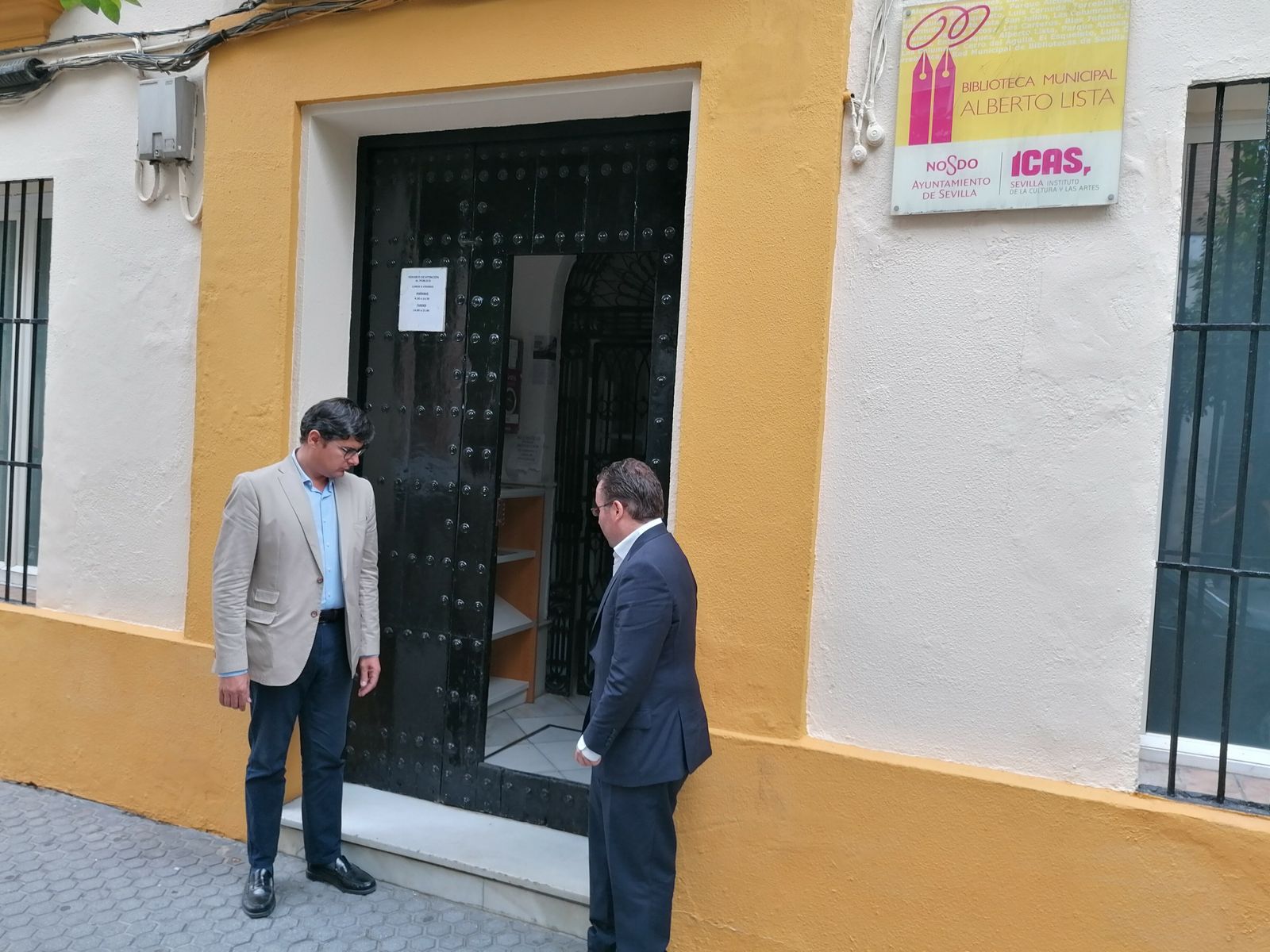 Los concejales de Ciudadanos en la entrada de la biblioteca, donde un escalón y la puerta metálica dificultan la entrada.
