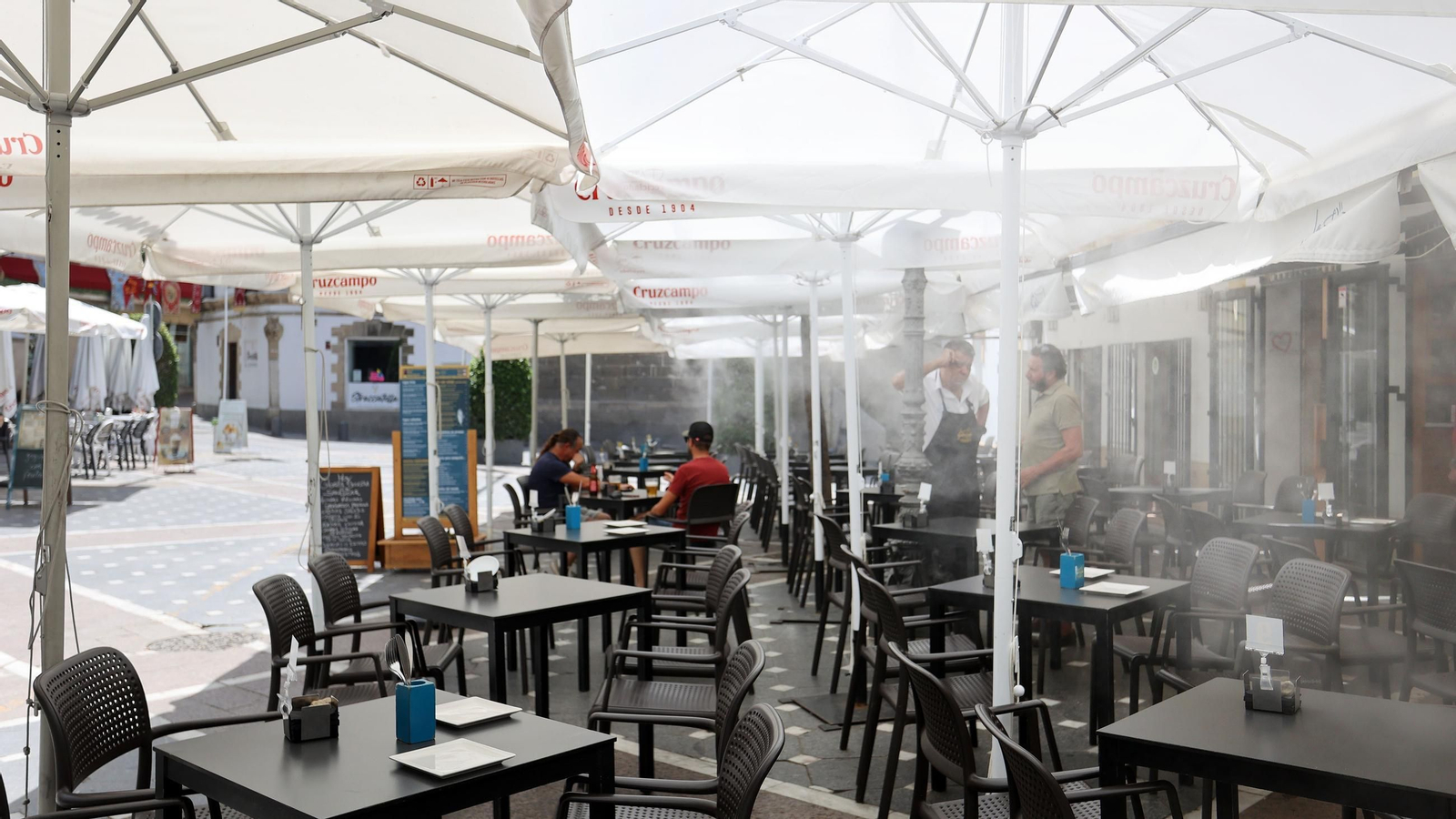 Un bar de la plaza del Progreso con aspersores de agua para paliar el calor