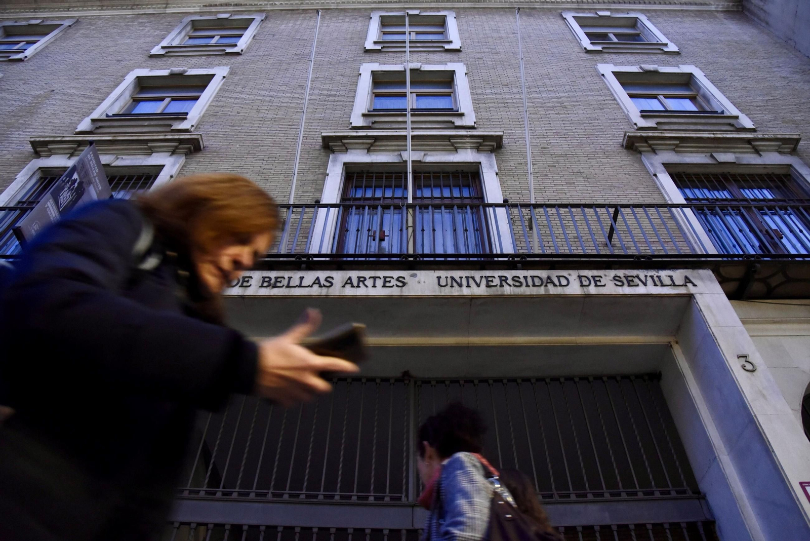 Varias personas pasan delante del acceso principal a la Facultad de Bellas Artes, en la calle Laraña.
