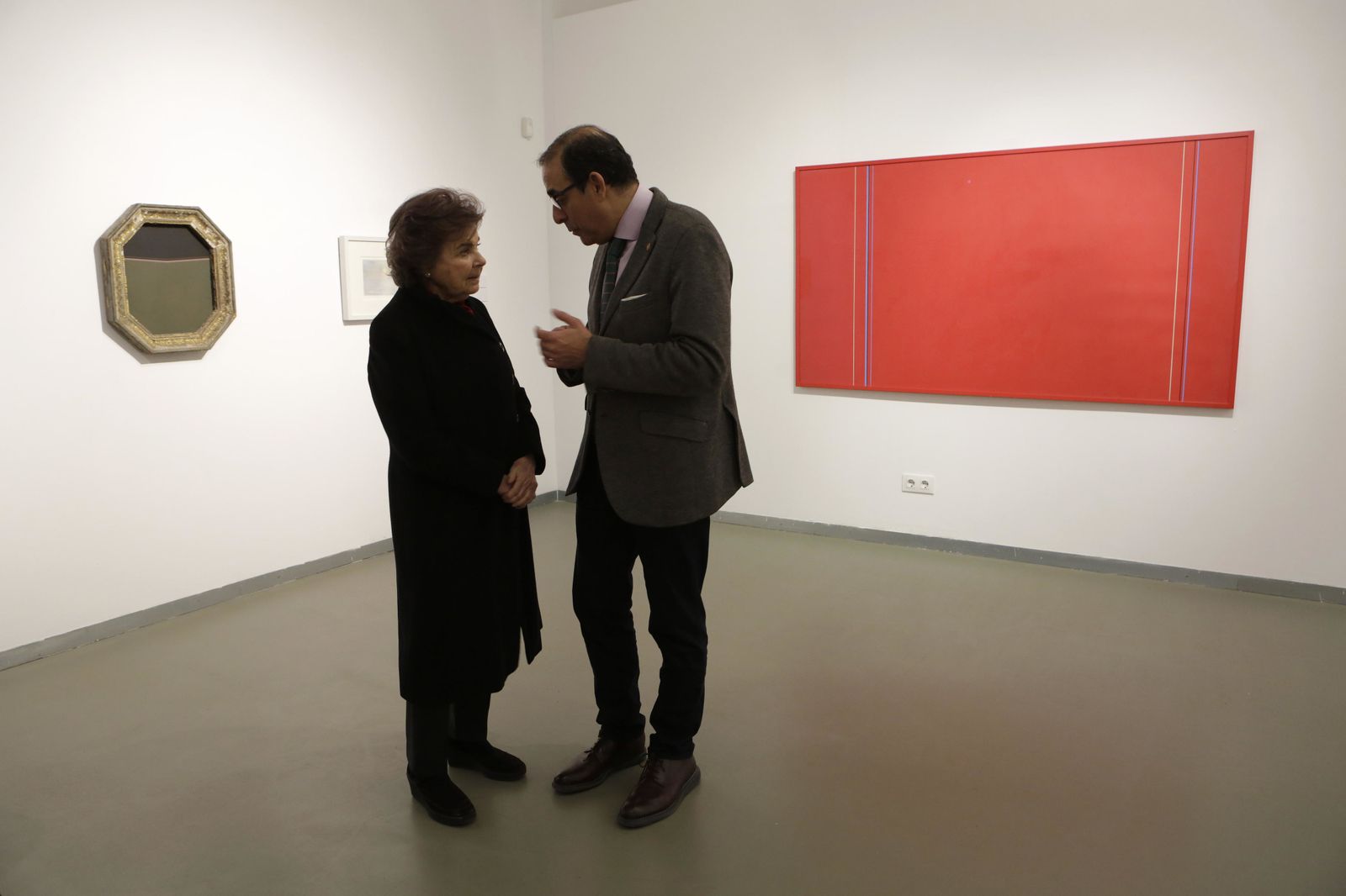 Carmen Laffón conversa con el rector de la Universidad de Sevilla ante un lienzo rojo de Pepe Soto.