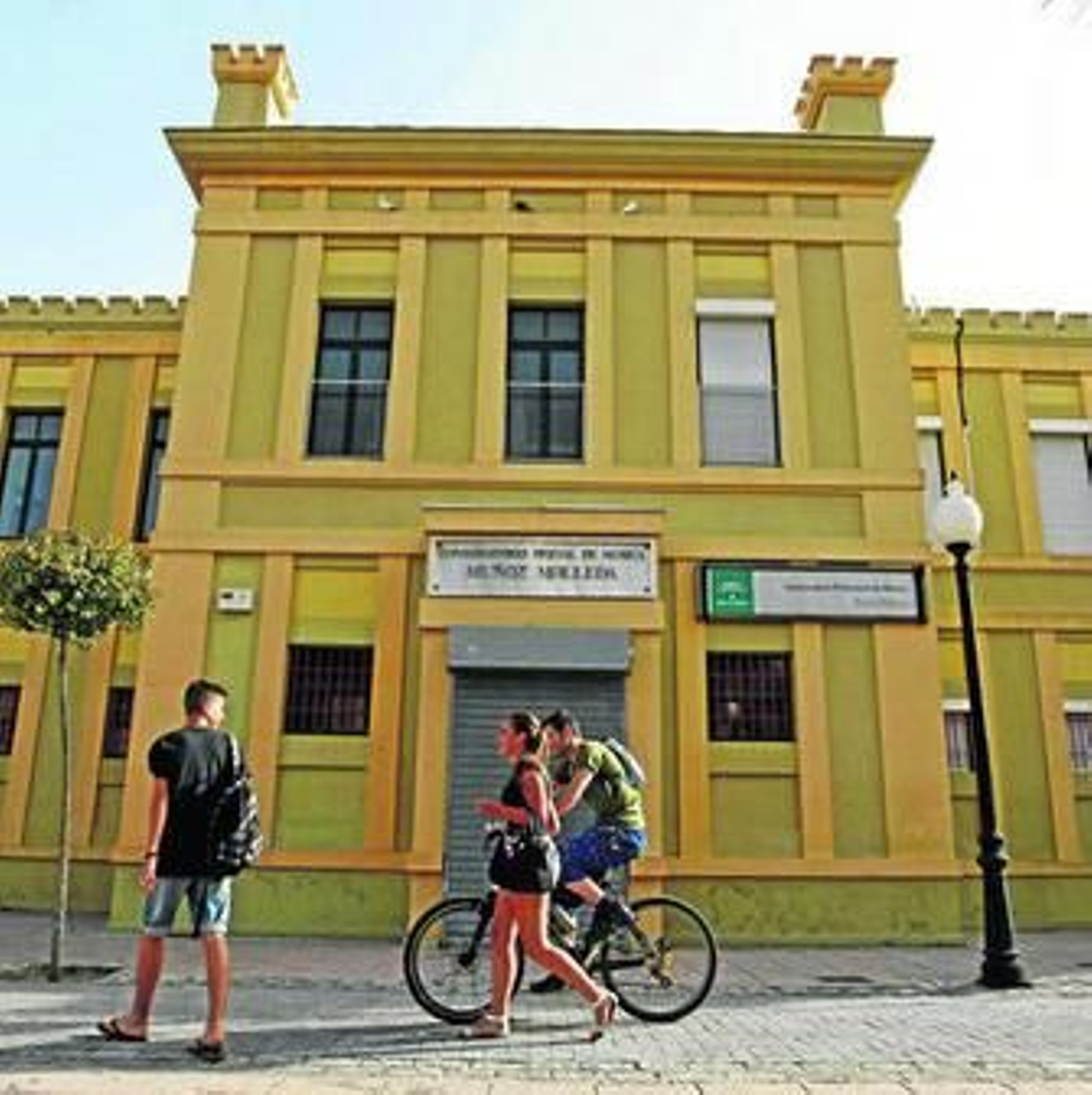 Tres jóvenes transitan por delante del edificio del conservatorio linense.