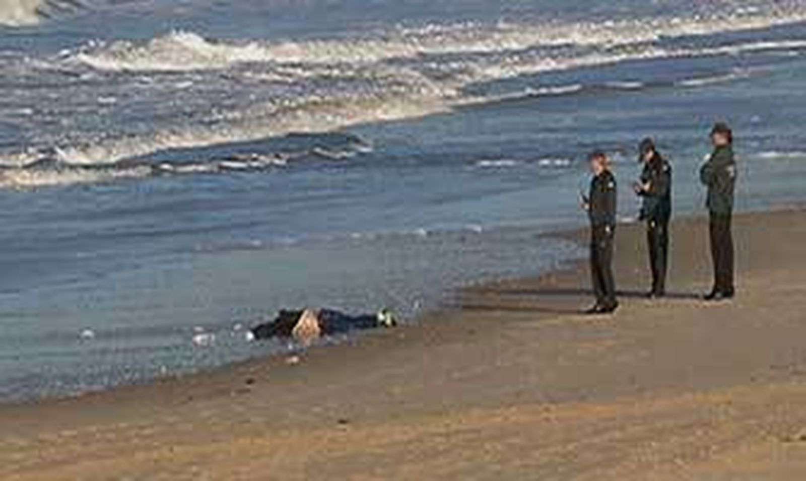 Tres agentes de la Guardia Civil custodian el cuerpo del presunto narcotraficante marroquí que apareció ayer en la playa del Novo Sancti Petri.
