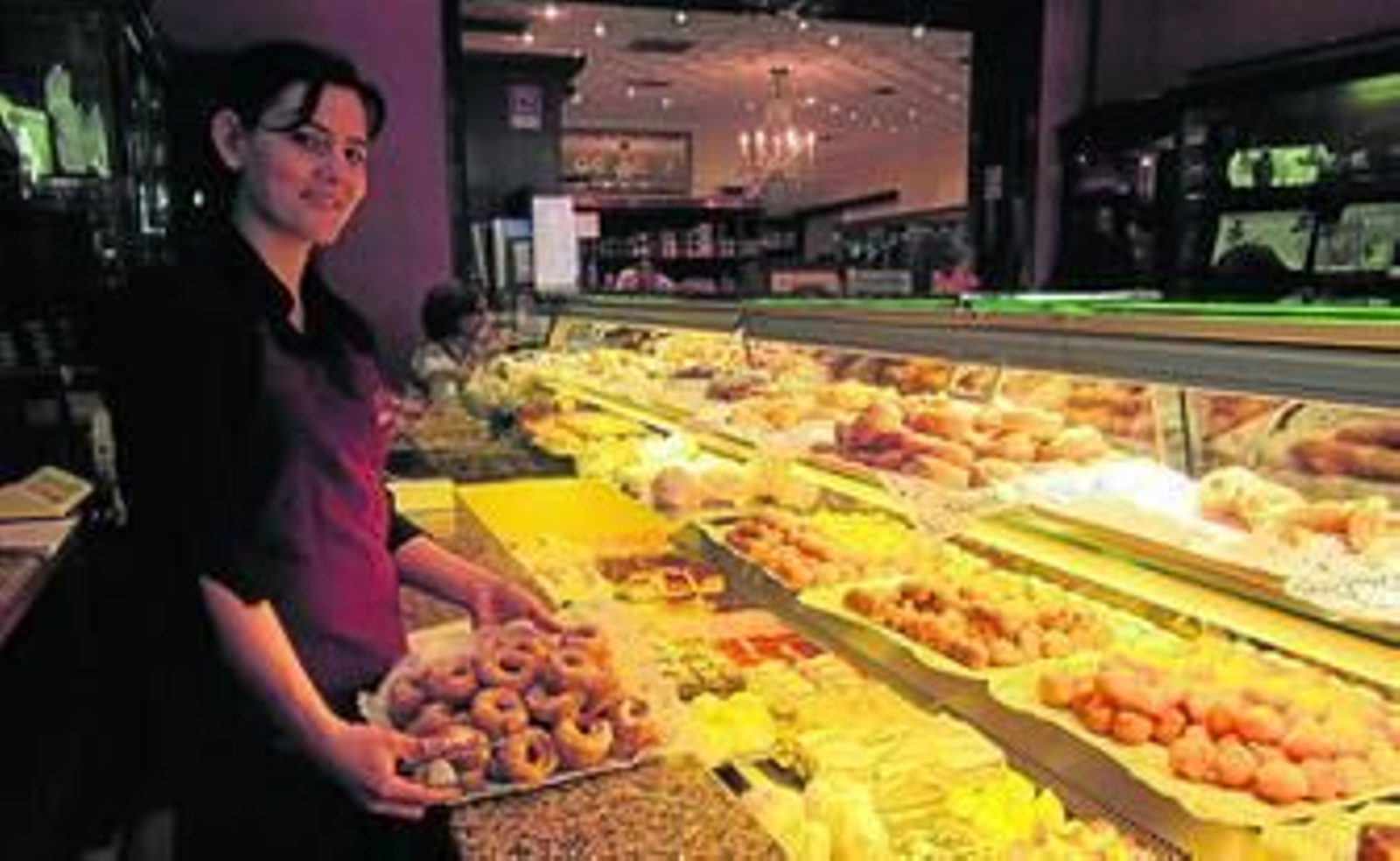 Una de las empleadas de La Dulce Alianza coloca algunos roscos en la vitrina.