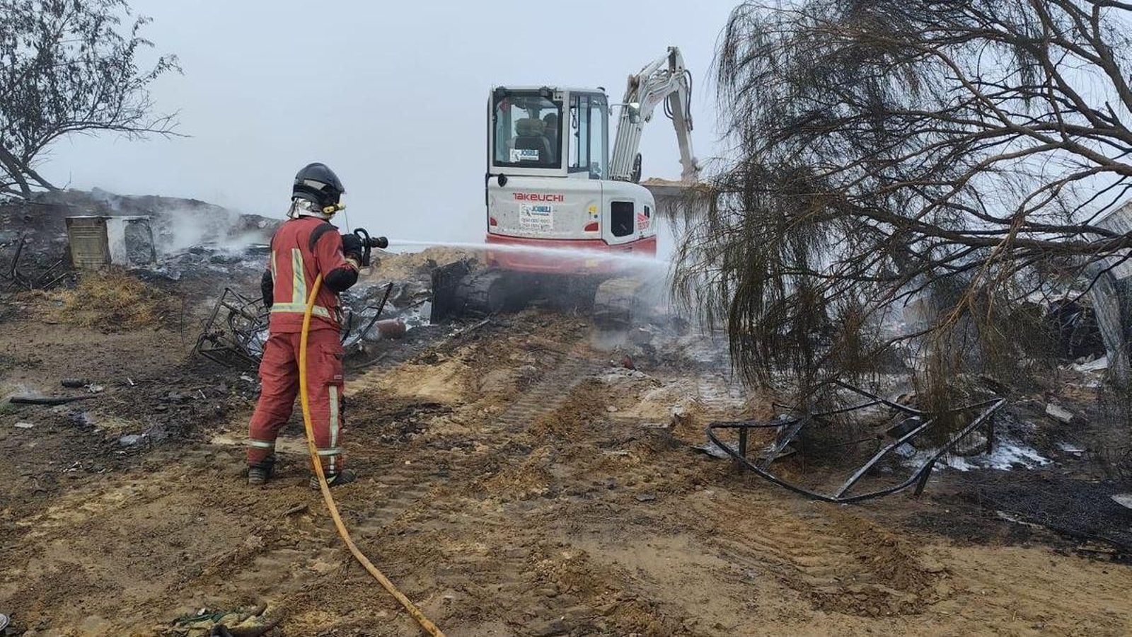Bomberos actuando en el campamento incendiado.