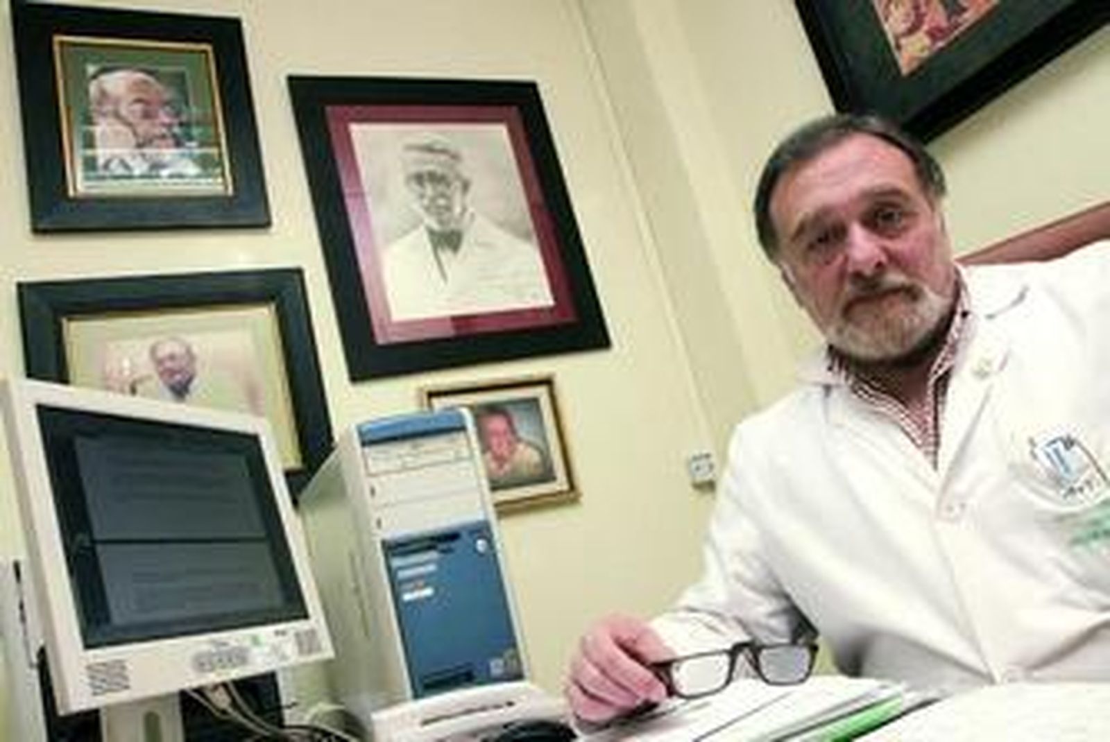 El ginecólogo, en su consulta, con las fotografías de los que fueron sus maestros al fondo.
