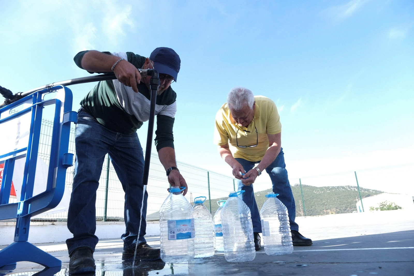 Dos personas llenan garrafas de agua potable en Espiel.