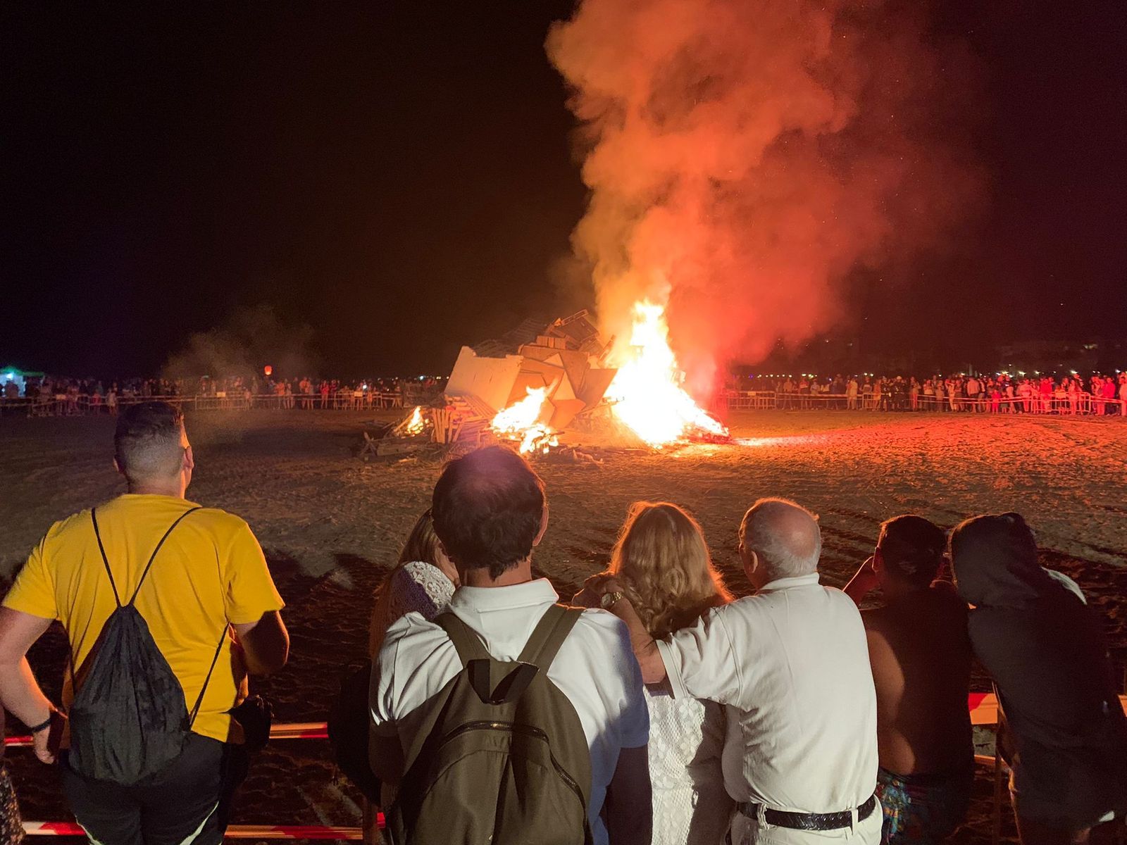 Varias personas observan el fuego de una hoguera en Motril.