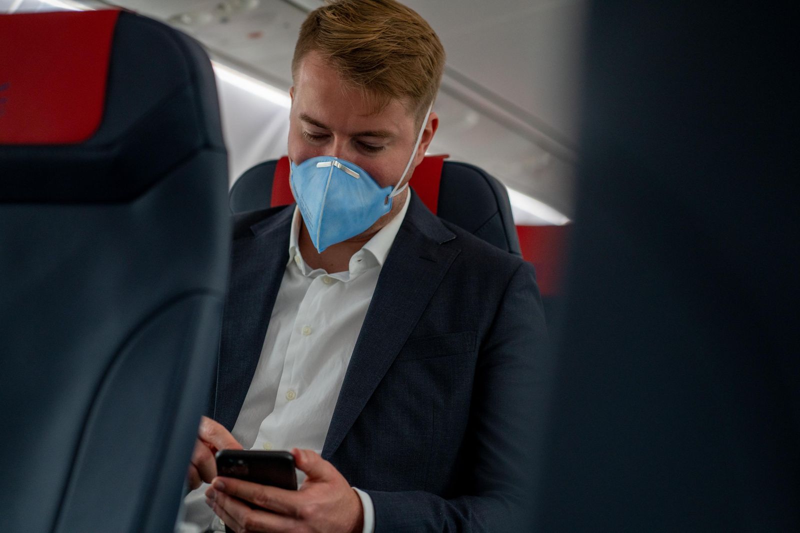 Un viajero con su mascarilla en el interior de un avión