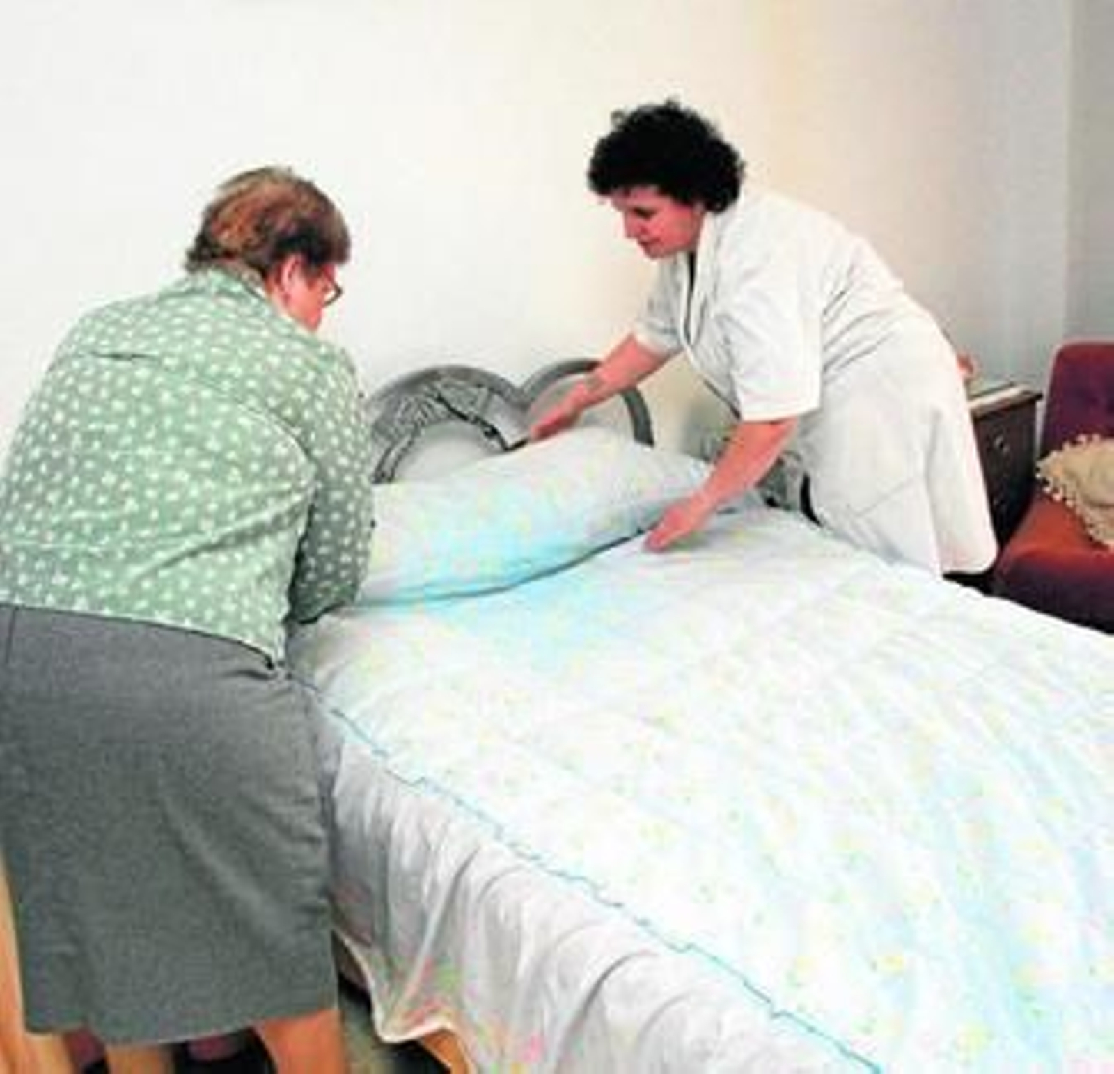 Una trabajadora de ayuda a domicilio auxilia a una anciana.