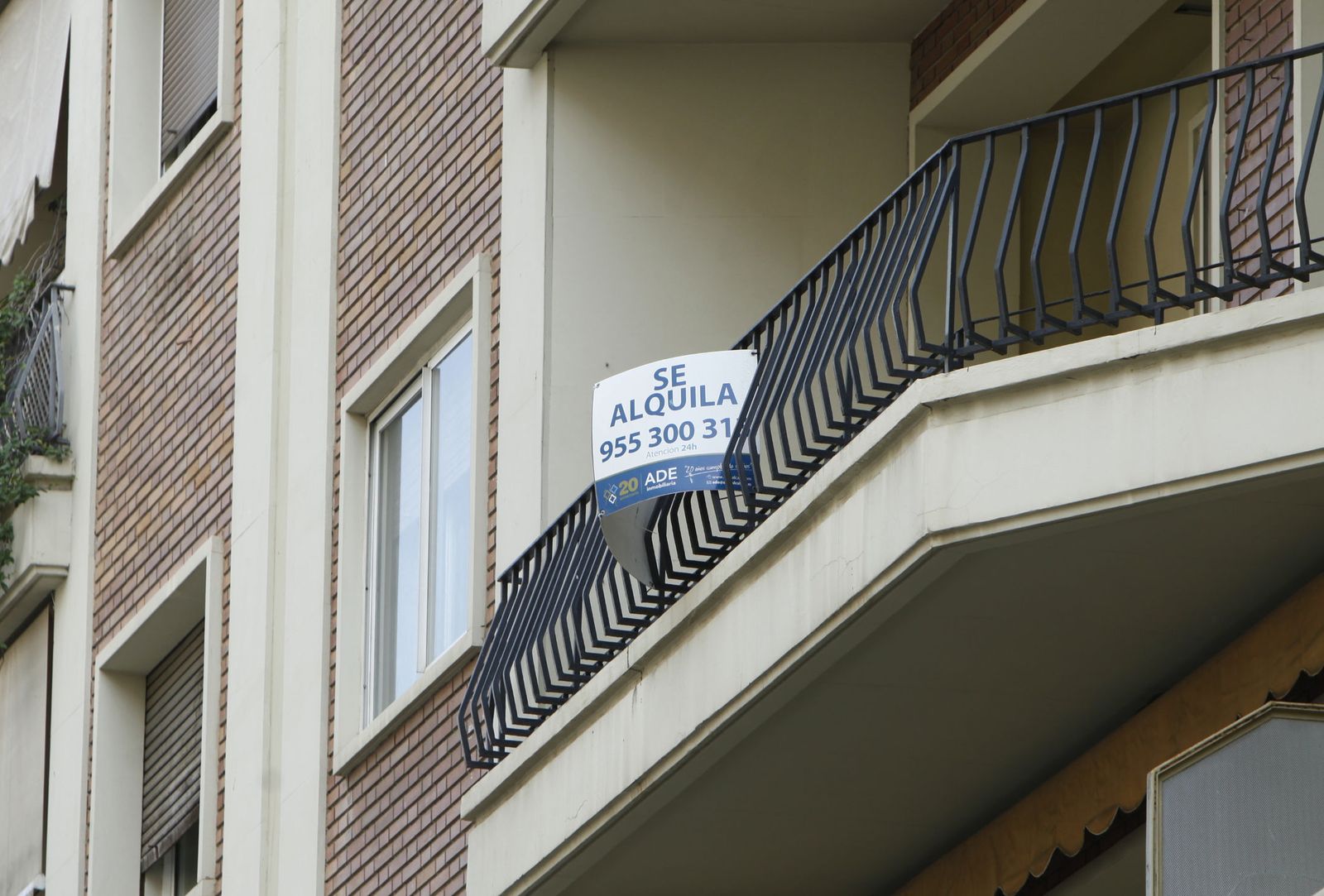 Cartel con el anuncio de un alquiler en un balcón de una vivienda.