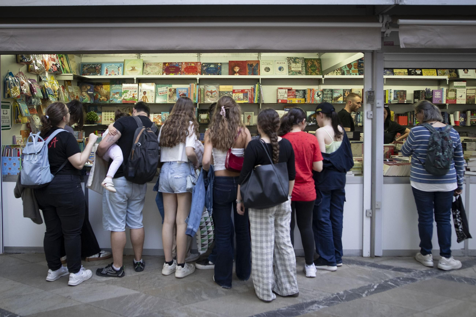 Varias personas se agolpan ante una caseta de la Feria del Libro.