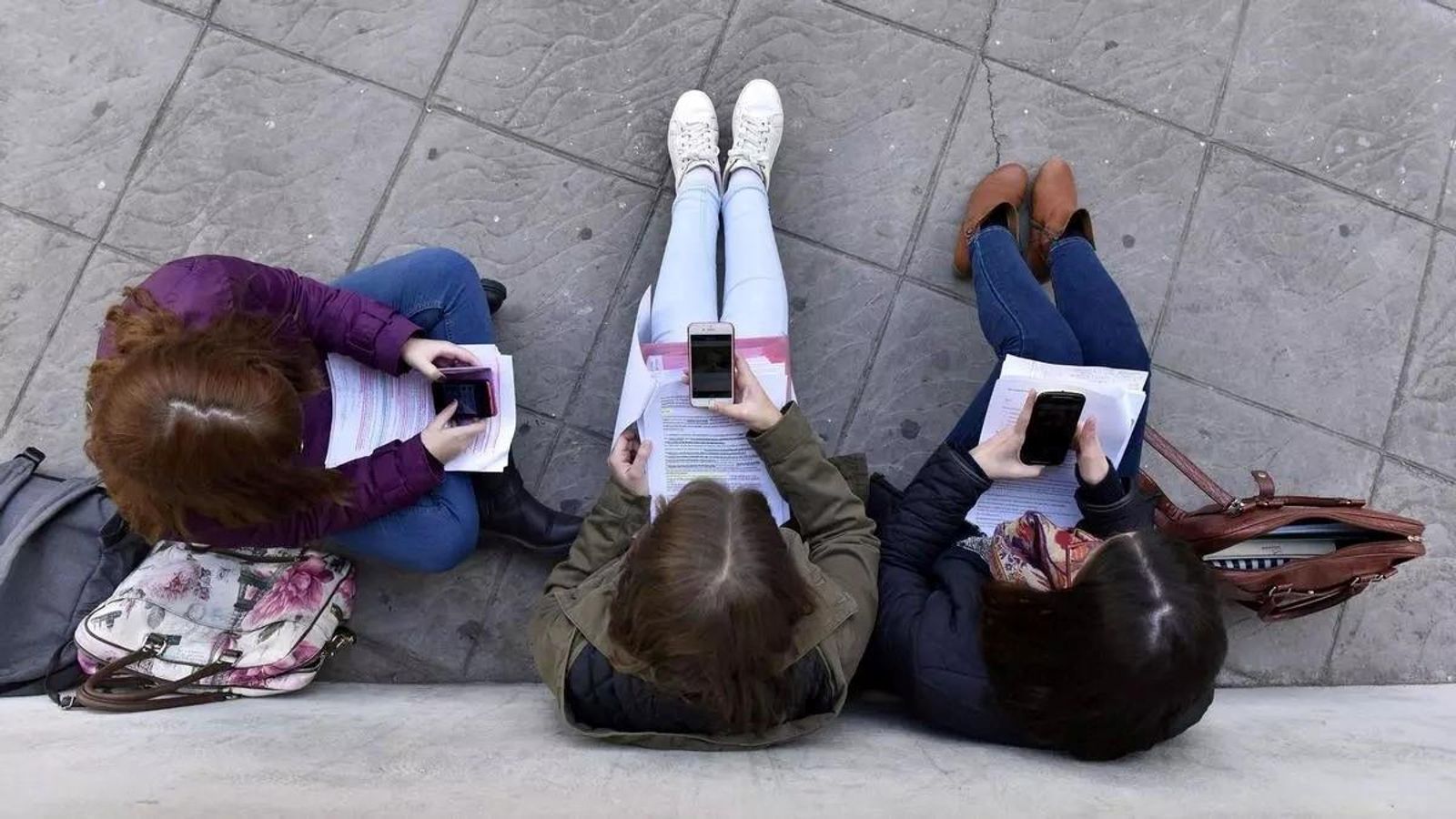 Estudiantes utilizan el móvil.