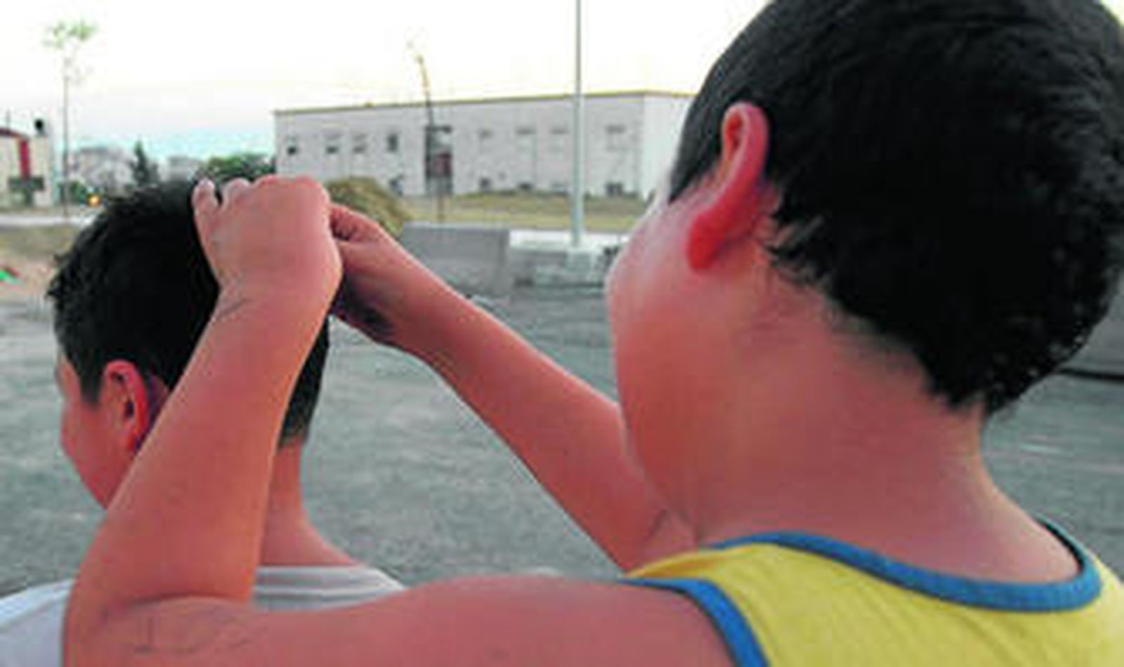 Un niño le revisa a otro el pelo a las puertas del colegio.