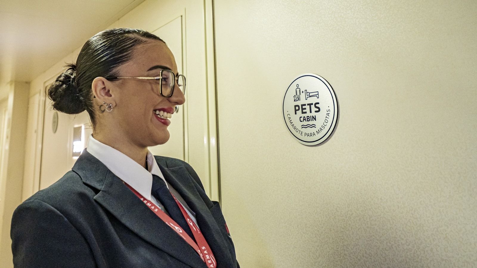 Una de las azafatas del Volcán de Tinamar, junto a un letrero que avisa de que el barco cuenta con habitaciones preparadas para viajar con mascotas