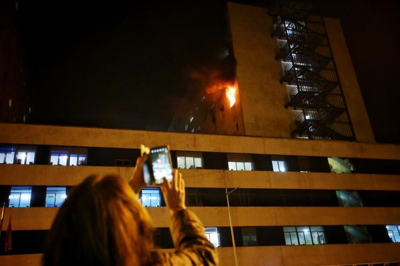 Una mujer graba con su teléfono el incendio en el hospital Puerta del Mar.